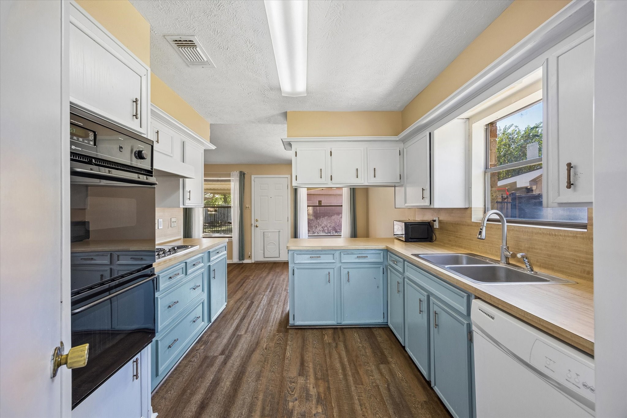 Bright and inviting kitchen with pastel blue cabinets, ample counter space, featuring large windows that fill the room with natural light.