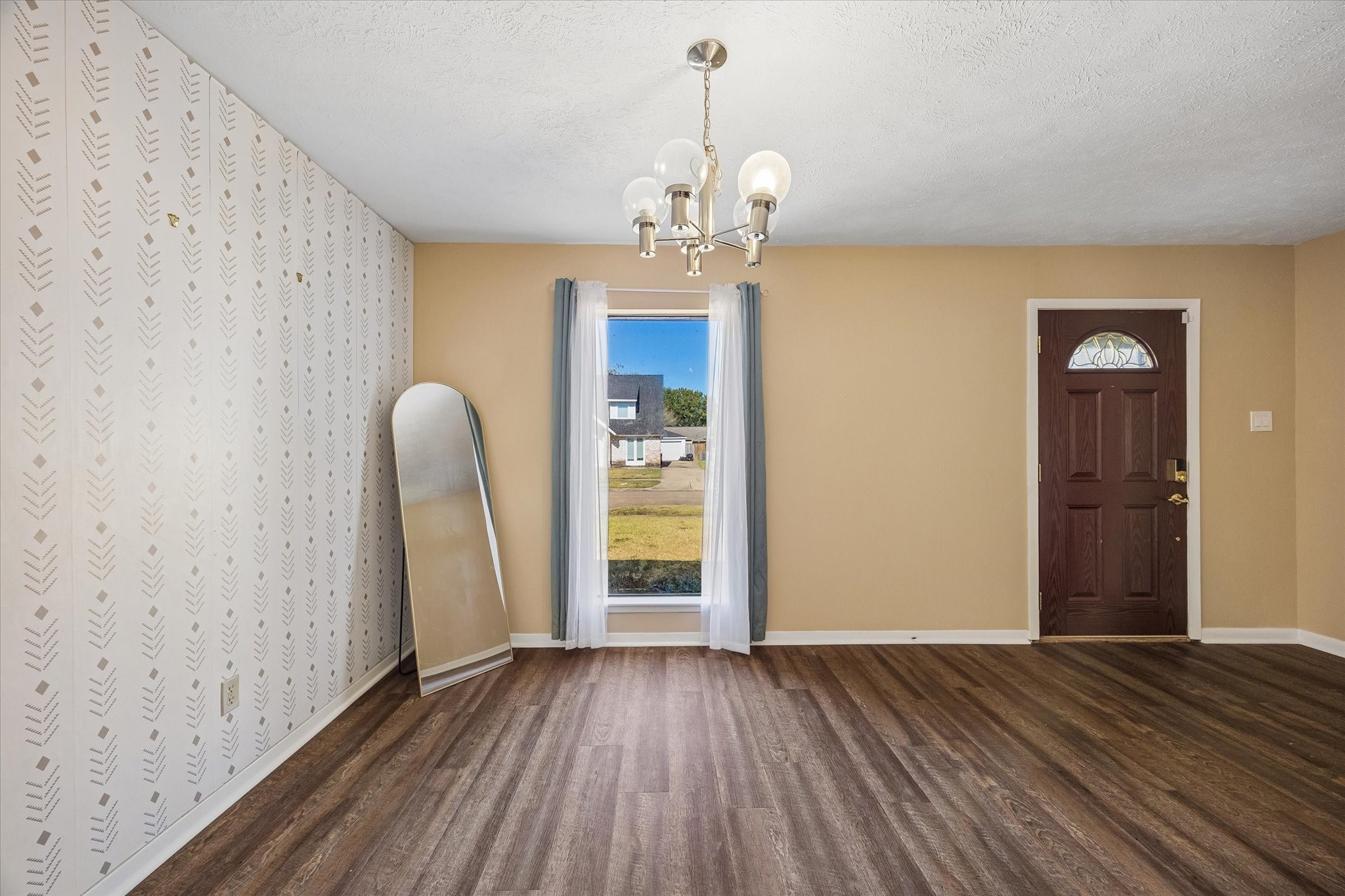 Charming entryway features elegant flooring, a stylish accent wall, and a classic chandelier, creating a welcoming atmosphere.
