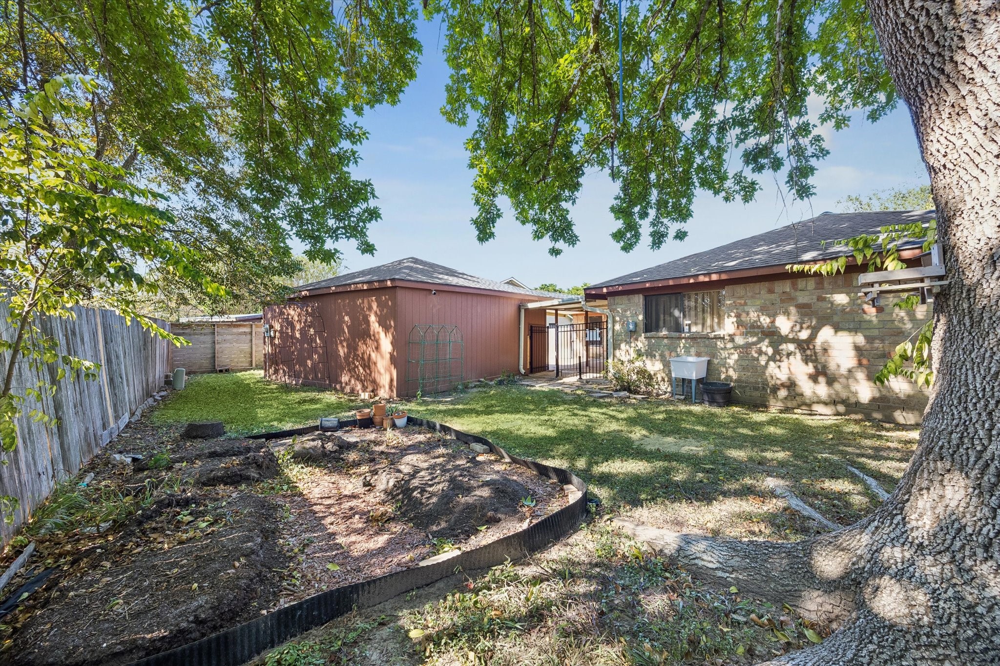 Charming backyard oasis with mature trees, a cozy patio area, and a spacious lawn perfect for gardening or relaxation.