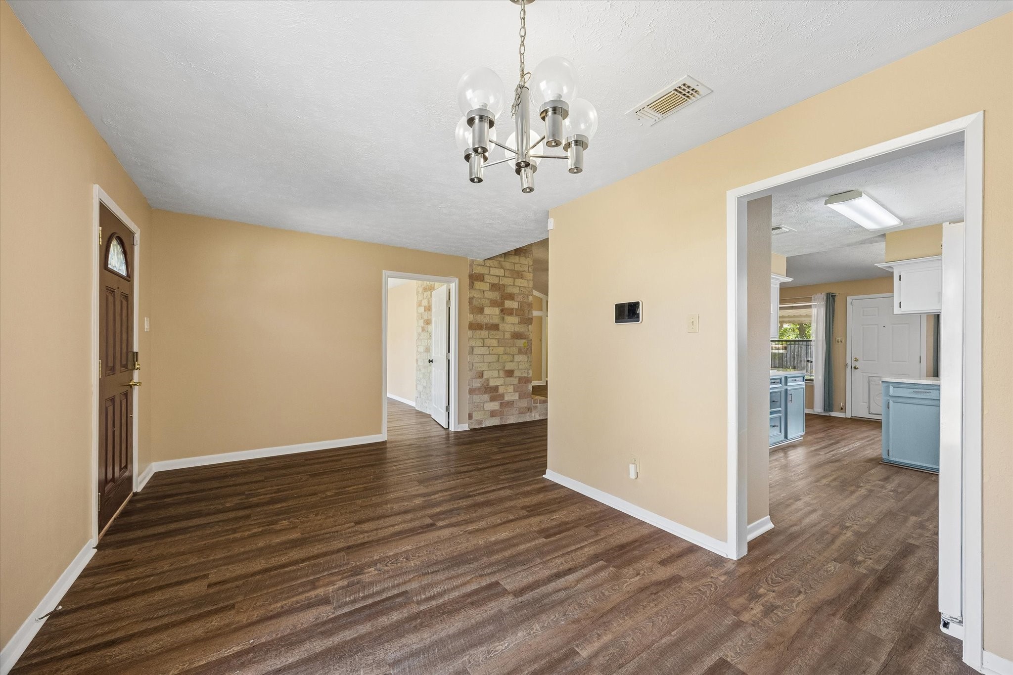 Charming entryway with warm wood floors and neutral walls, leading to a bright, spacious kitchen.