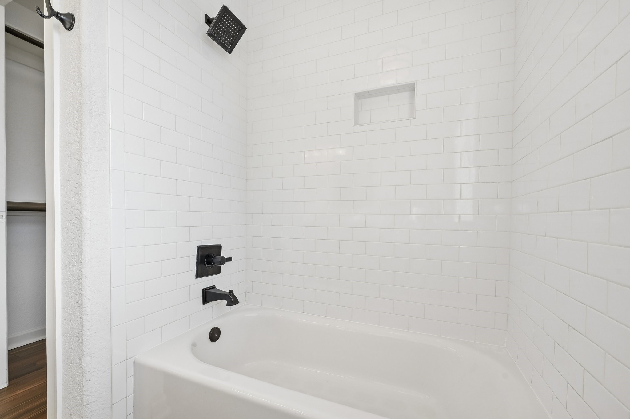 Bright and modern bathroom featuring a sleek white subway tile design, complemented by matte black fixtures and a spacious tub for relaxation.