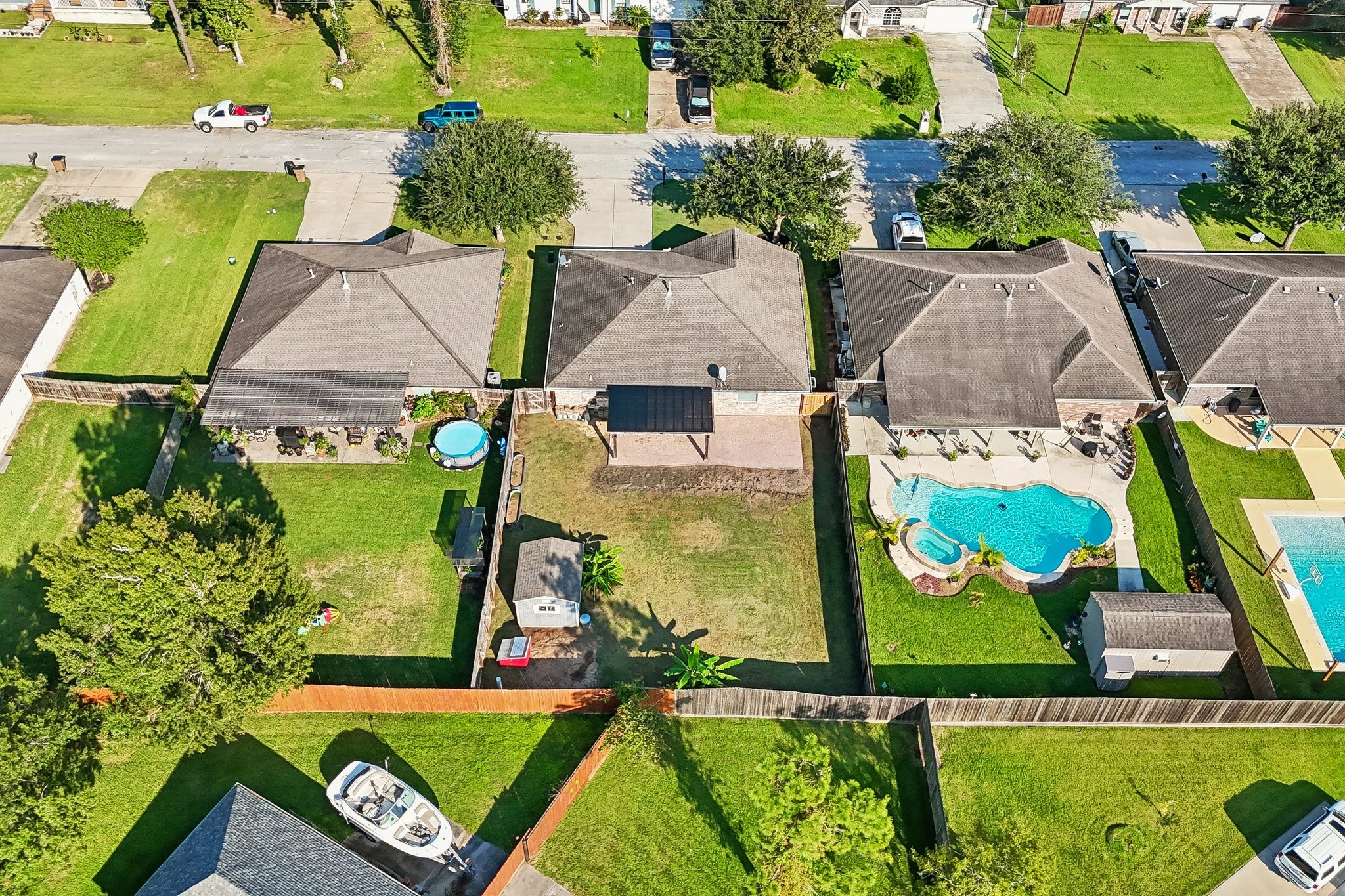 Charming suburban neighborhood with well-maintained homes featuring spacious backyards. A standout property includes a sparkling pool and a cozy patio area, perfect for outdoor relaxation and entertaining.