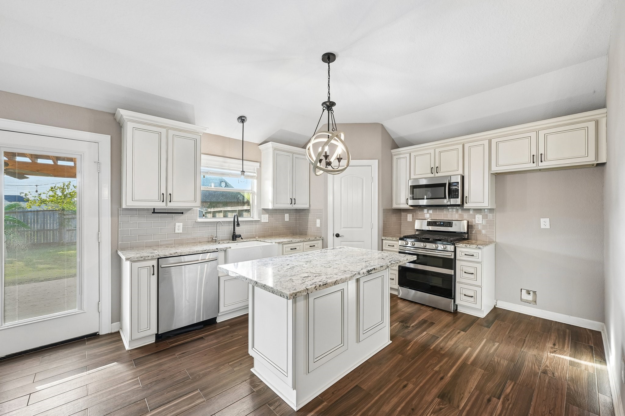 Bright and inviting kitchen with modern stainless steel appliances, elegant white cabinetry, and a central island under stylish pendant lighting.