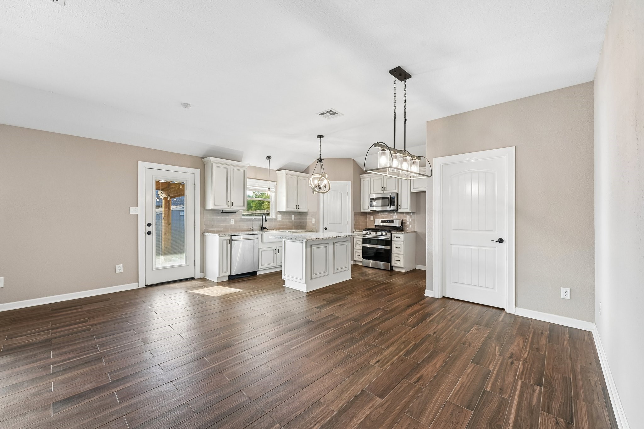 Open-concept kitchen and dining area with elegant wood-look tile flooring, modern light fixtures, and a bright, airy feel.