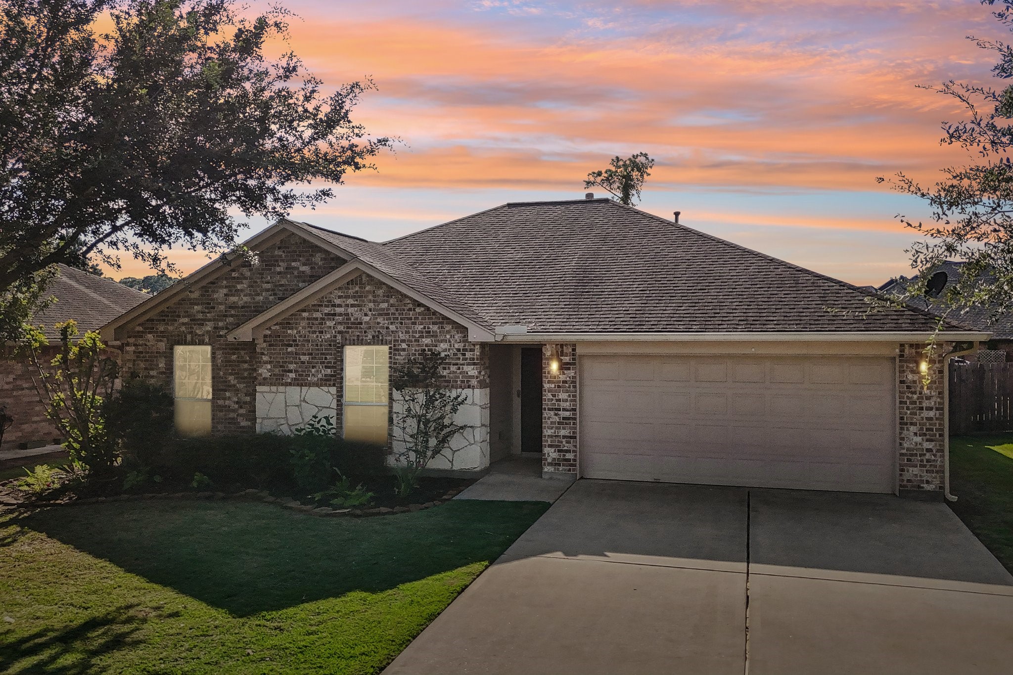 Charming brick home with a spacious two-car garage, nestled in a serene neighborhood. The beautifully manicured lawn and mature trees create a welcoming curb appeal.