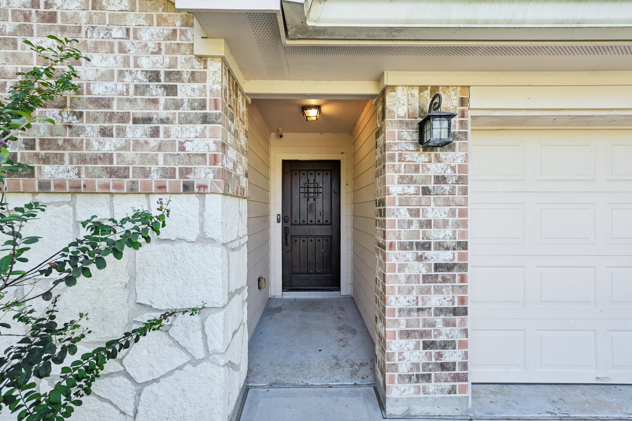 Charming entrance with a mix of brick and stone detailing, featuring a sturdy front door and a welcoming porch area.
