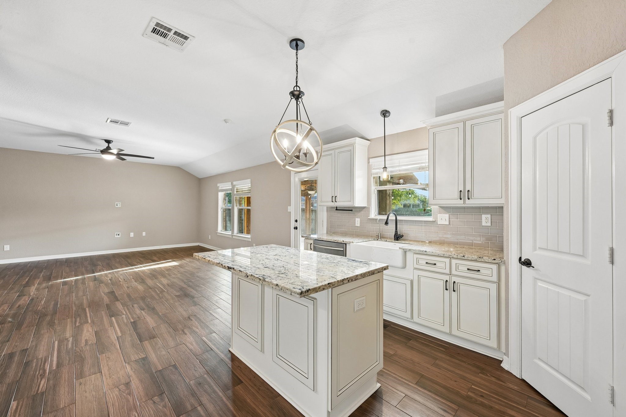 Stunning open-concept kitchen and living area featuring elegant hardwood floors, a large island with granite countertops, modern pendant lighting, and ample cabinetry for storage.