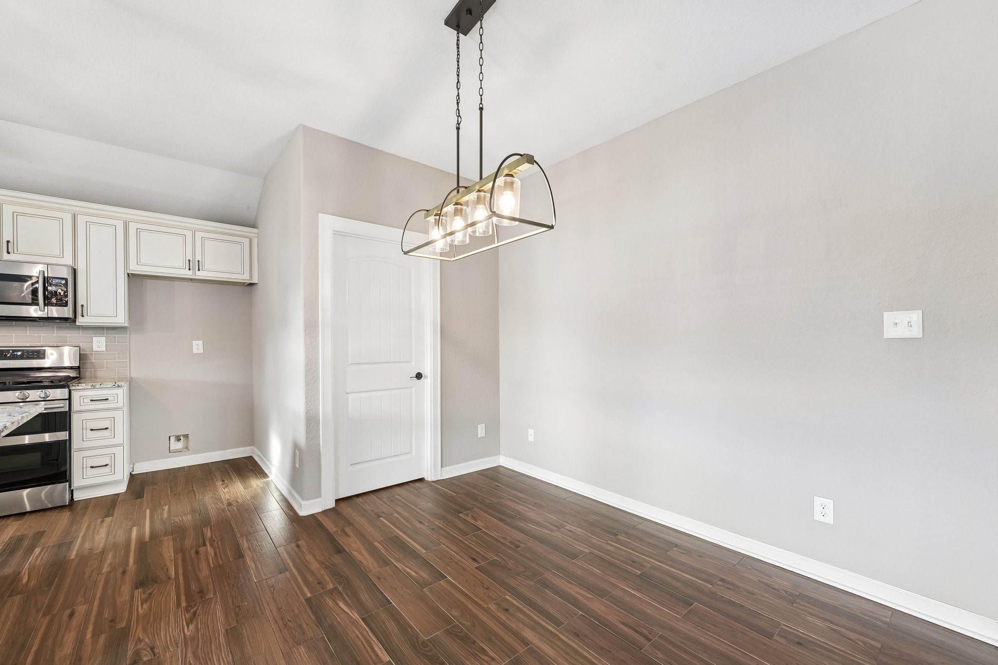 Elegant dining area with modern lighting, hardwood floors, and easy access to the stylish kitchen featuring stainless steel appliances and sleek cabinetry.