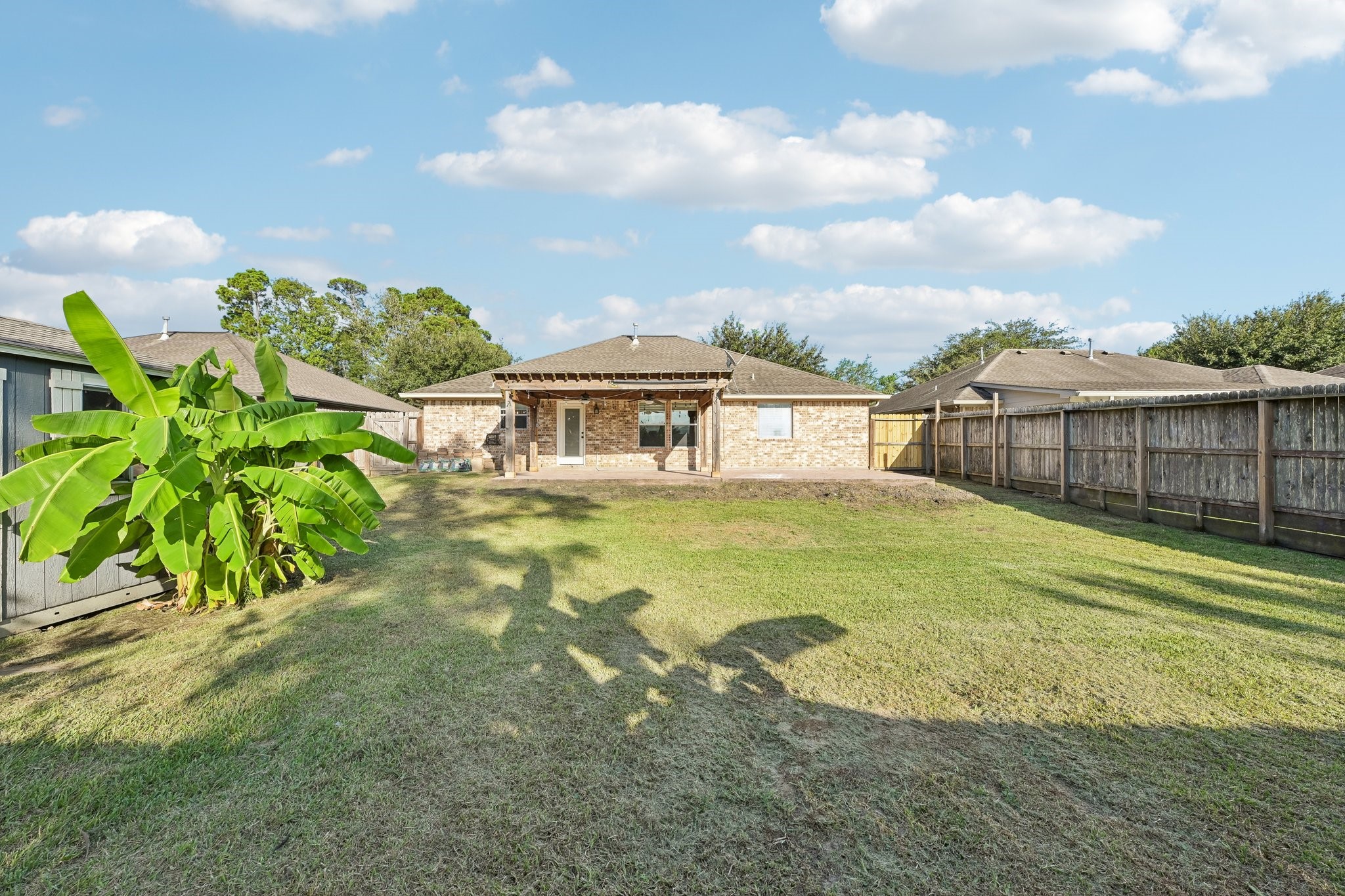 Spacious backyard with well-maintained lawn, privacy fence, and a charming brick exterior, perfect for outdoor activities and gatherings.