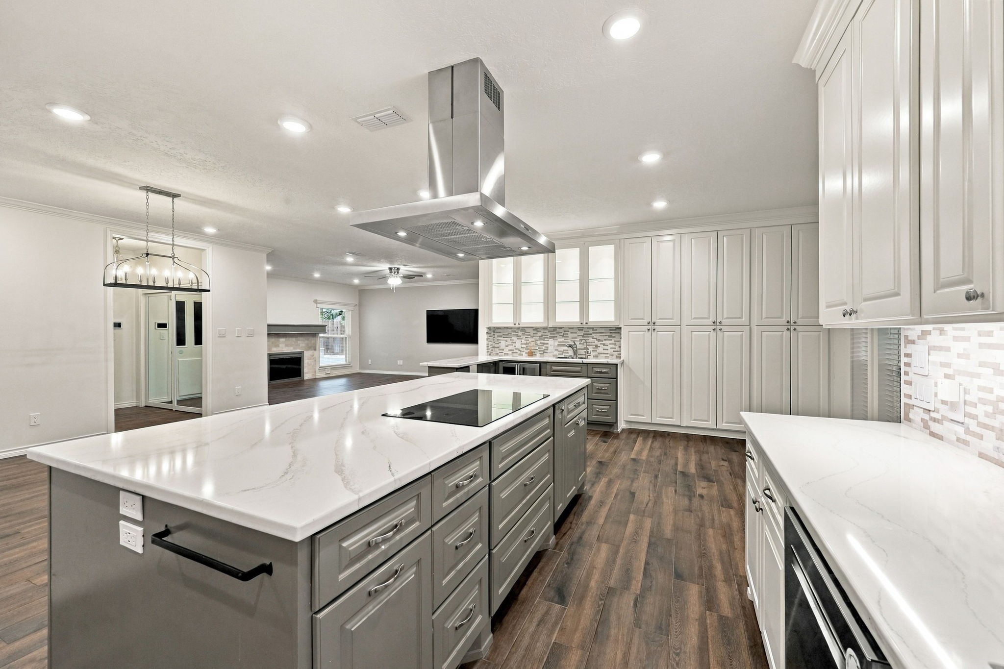 Updated kitchen featuring a large gray island, white cabinetry, stainless steel appliances, and contemporary lighting.