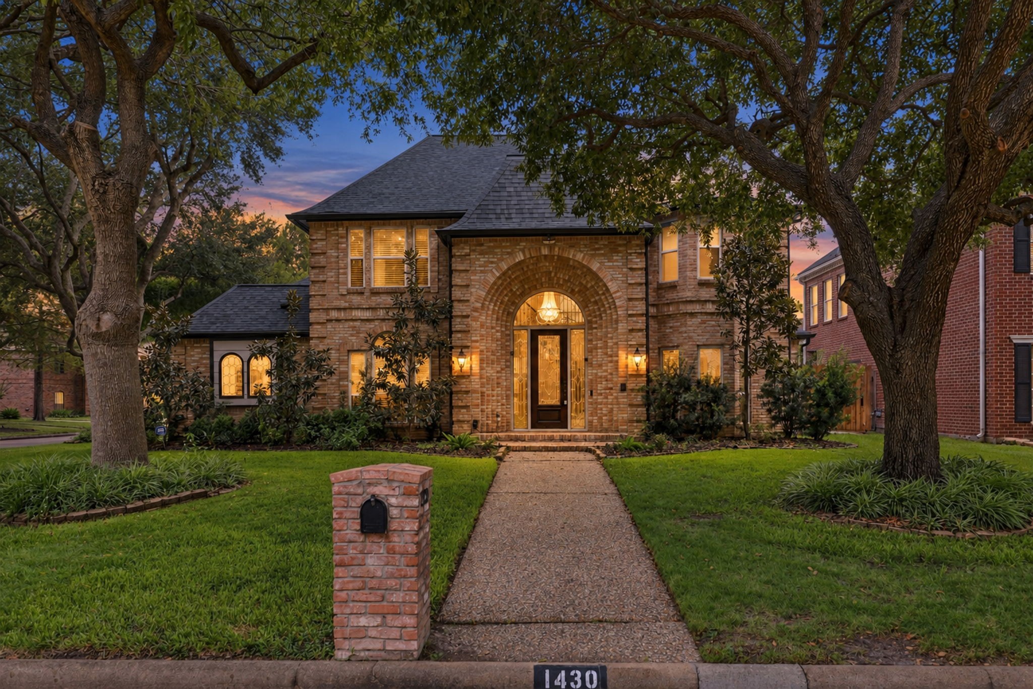 Stunning brick exterior illuminated at dusk, showcasing the elegant arched entryway and mature trees. Stunning brick exterior illuminated at dusk, showcasing the elegant arched entryway and mature trees.