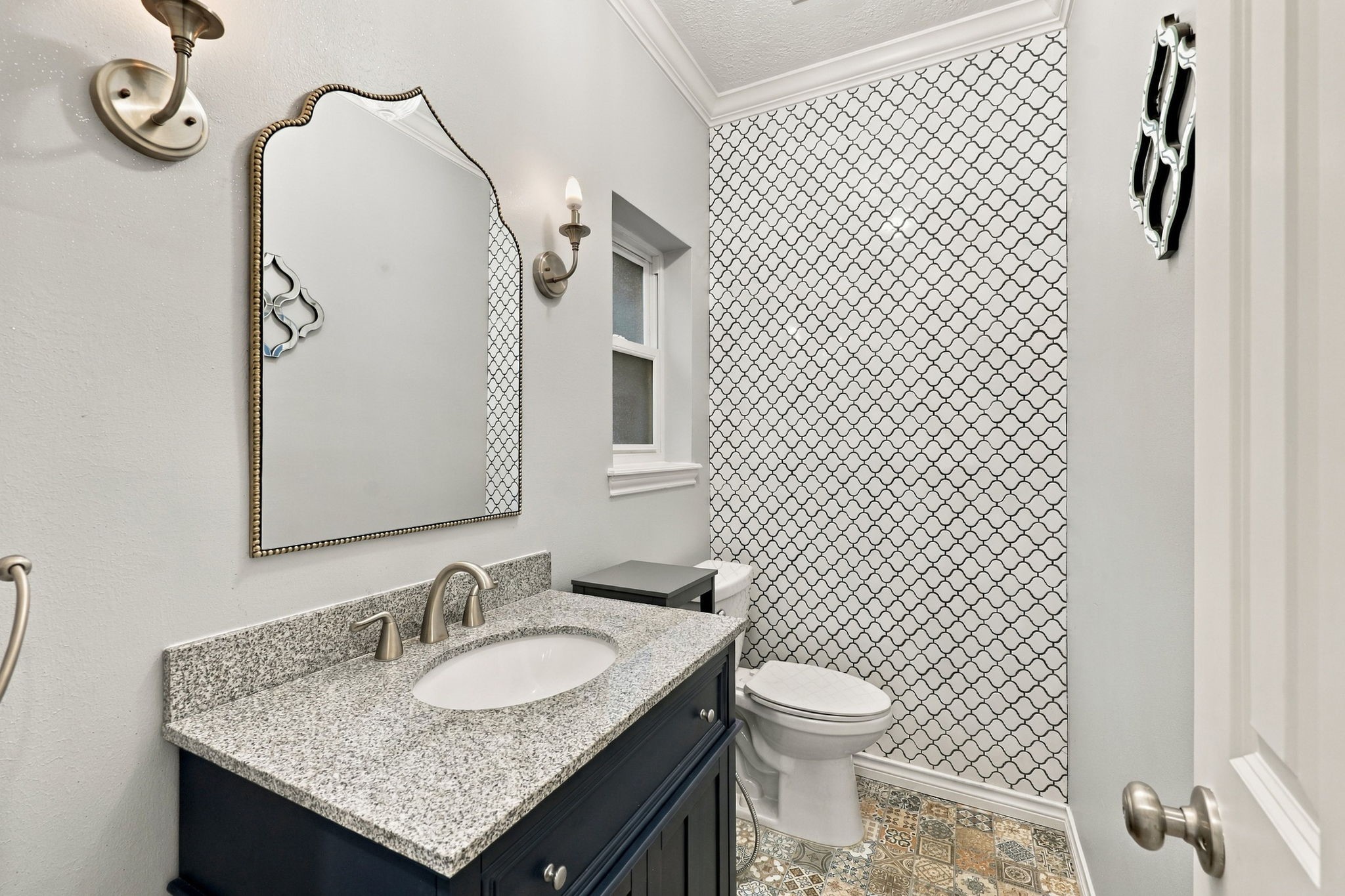 Stylish half bath featuring a dark vanity, granite countertop, decorative patterned tile, and modern fixtures.