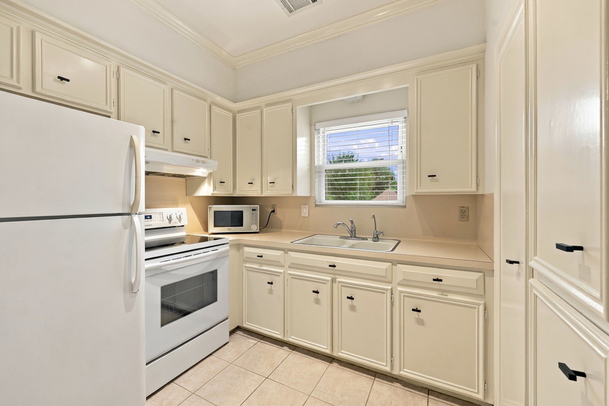 Garage Apt Full Kitchen featuring white cabinetry, ample cabinet storage, a window above the sink, and a functional layout.