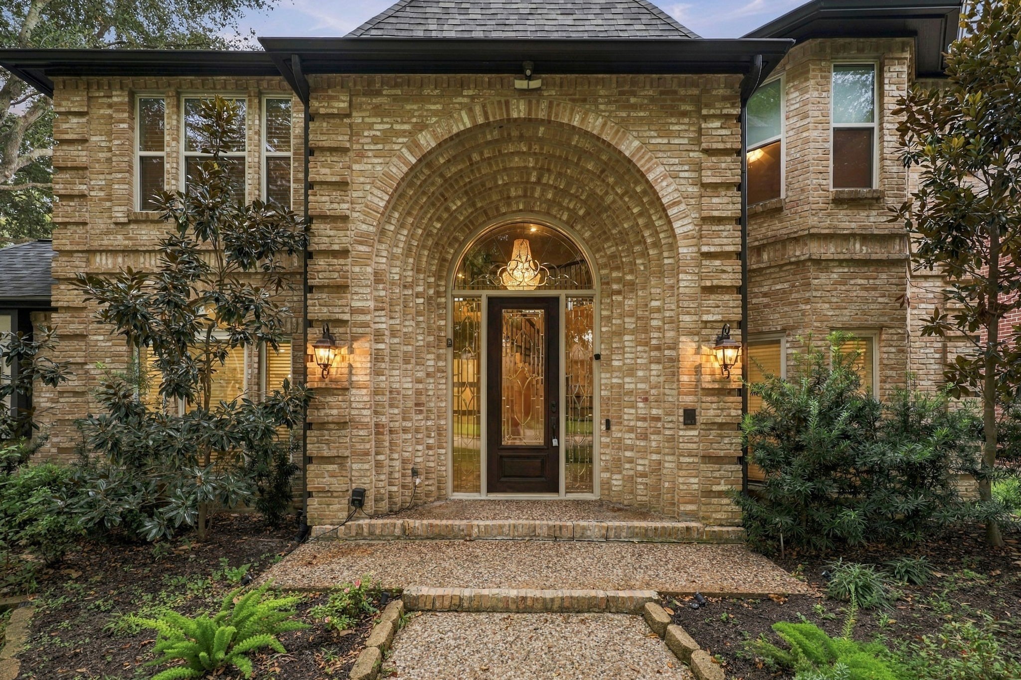 Close-up view of the home's distinctive brick architecture, arched windows, and manicured landscaping. Close-up view of the home's distinctive brick architecture, arched windows, and manicured landscaping.