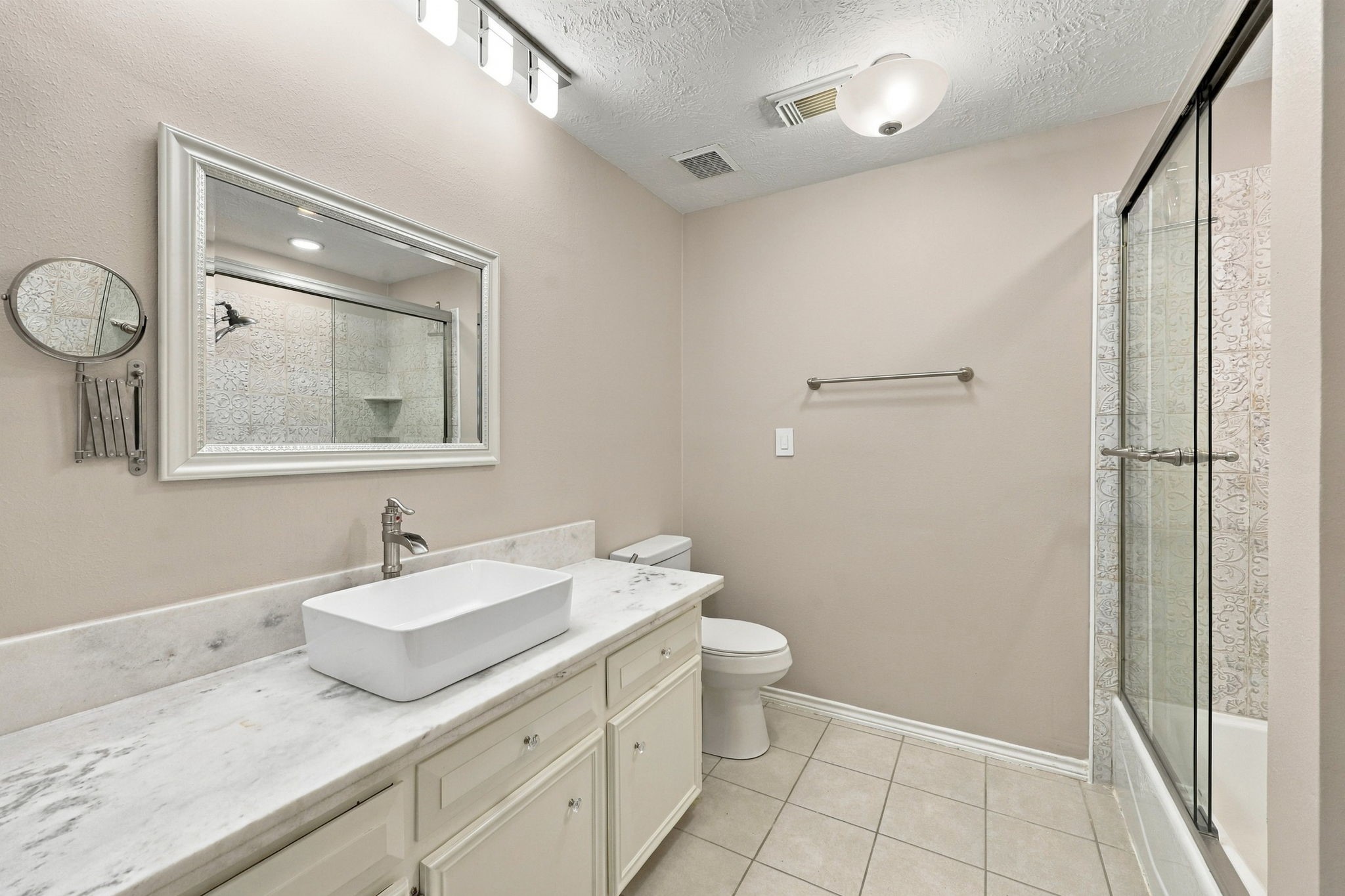 Contemporary bathroom with dual vessel sinks, a teal vanity, elegant mirrors, and a spacious walk-in shower.