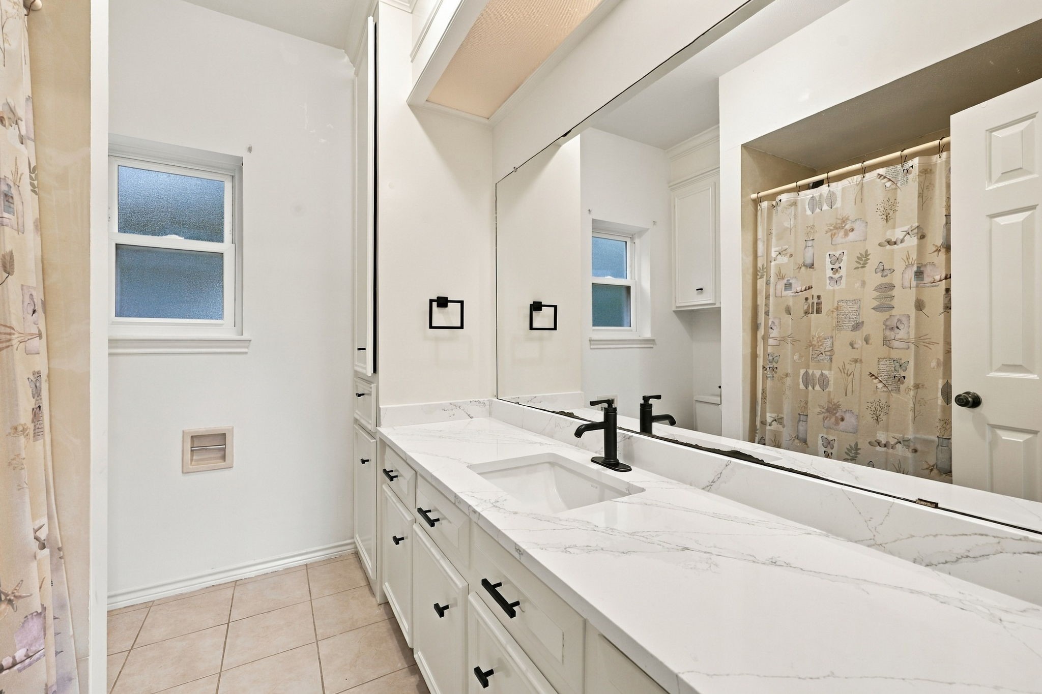 Garage Apt Full Bathroom featuring a modern vanity, decorative mirror, and a tub/shower combination with tile surround.