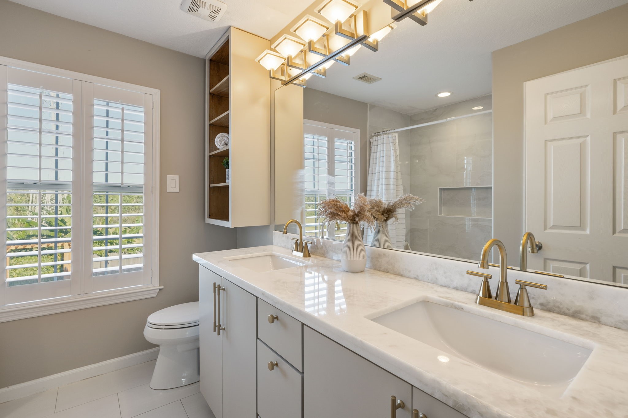 Elegant hallway bathroom featuring a dual-sink vanity with sleek marble countertops and gold fixture