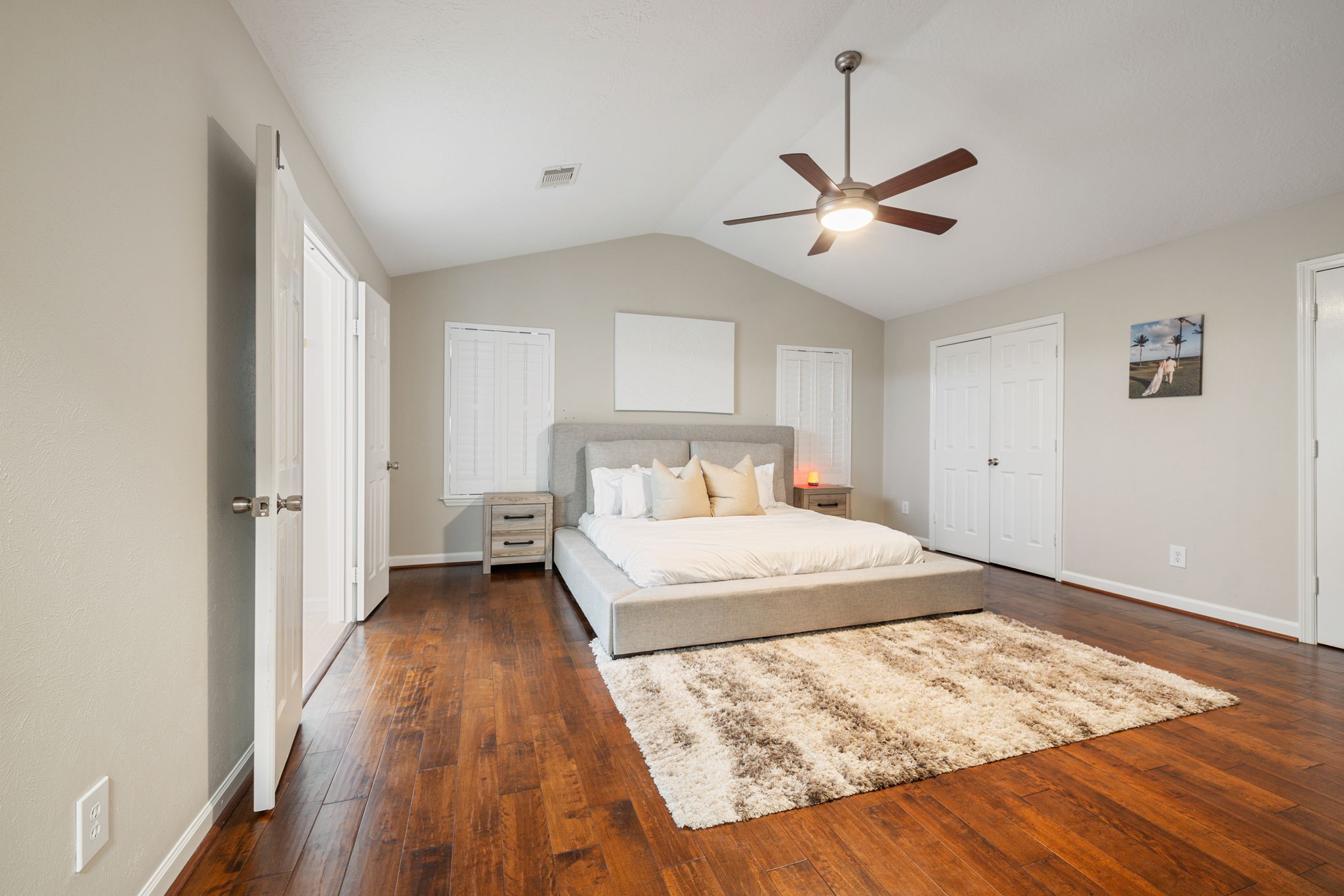 Generously sized primary suite featuring rich hardwood flooring, a vaulted ceiling, and two separate closets.