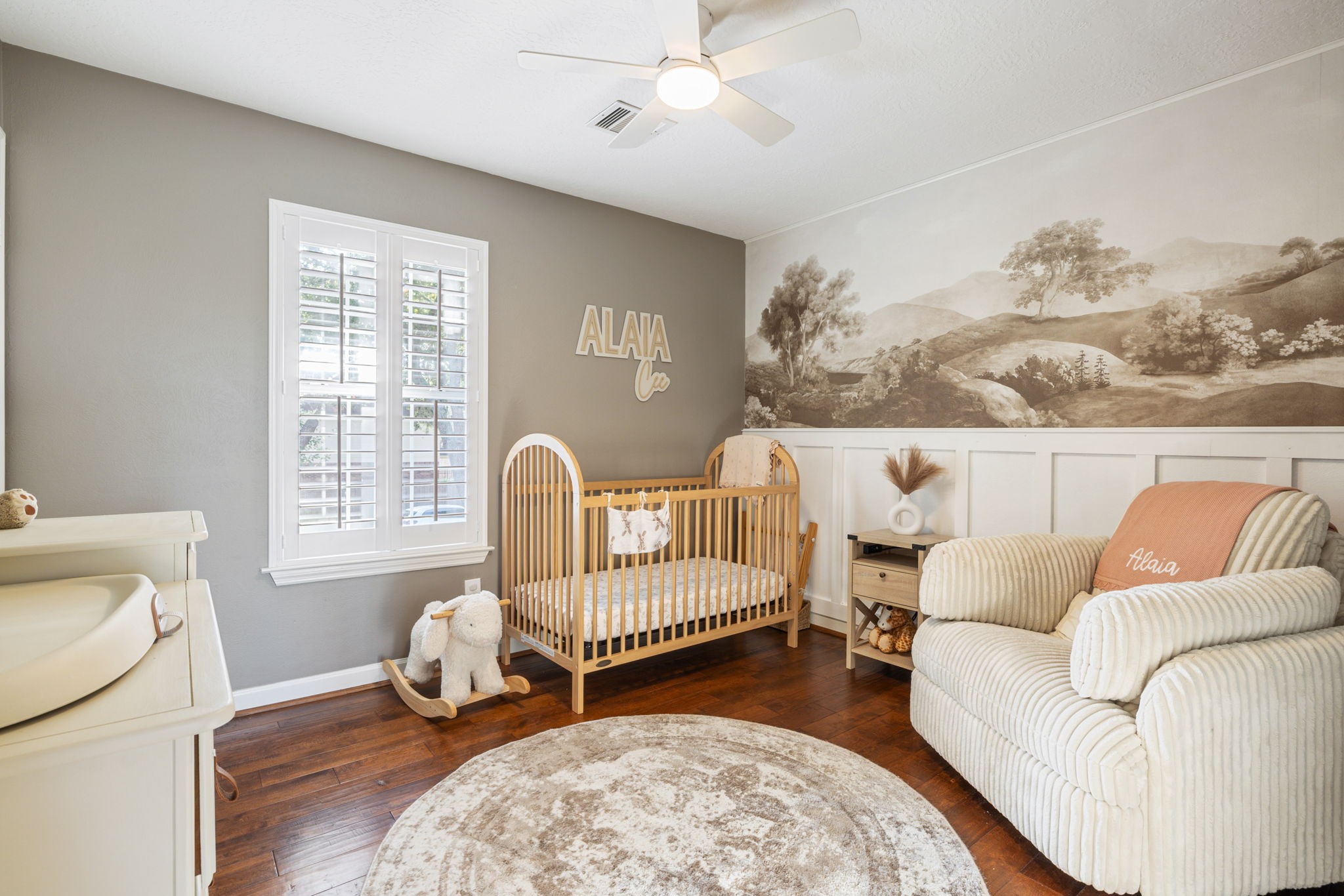 Charming secondary bedroom with hardwood flooring, plantation shutters, and decorative wall detailing.