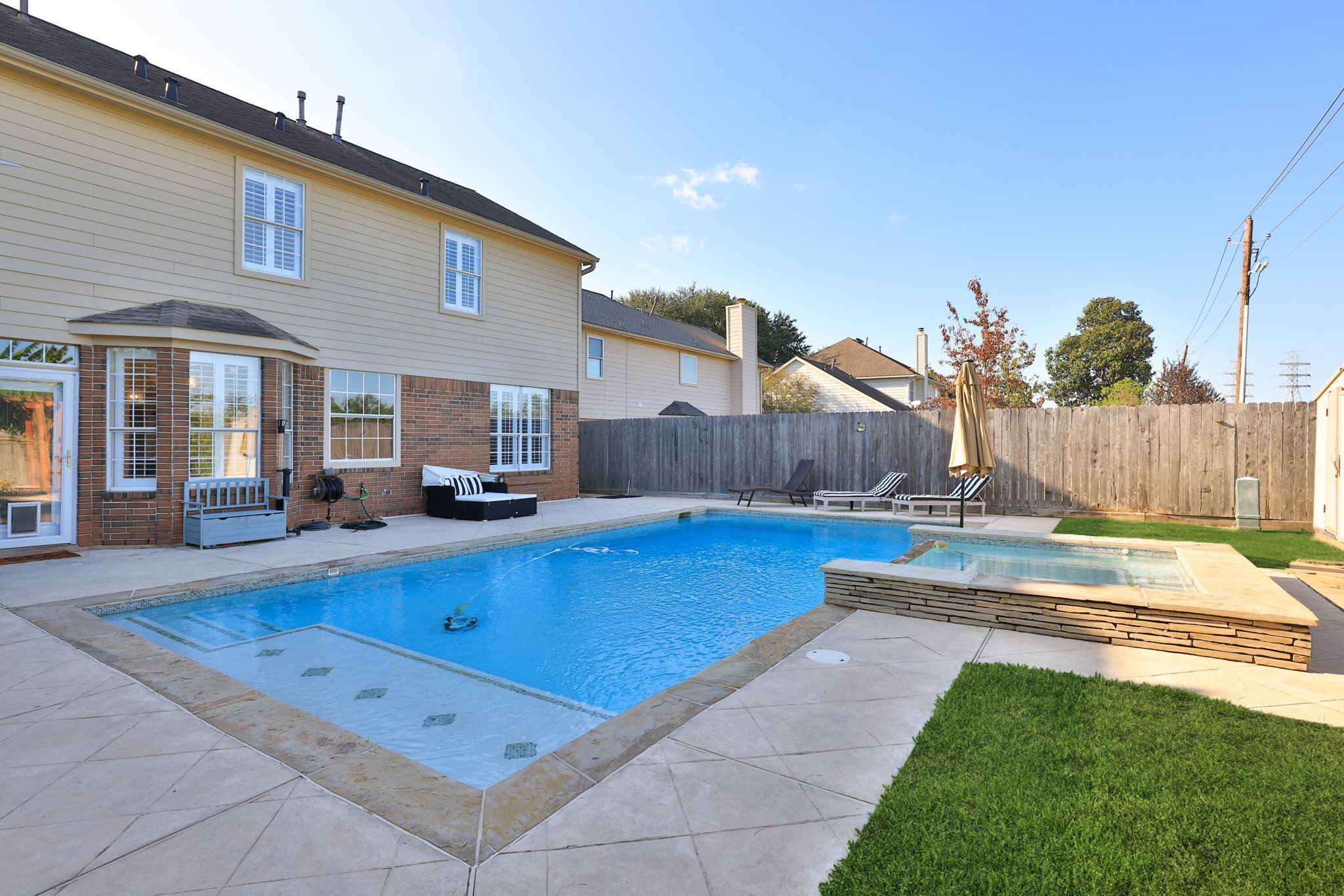 Your private backyard retreat awaits, complete with a sparkling swimming pool, hot tub, and expansive surrounding patio.
