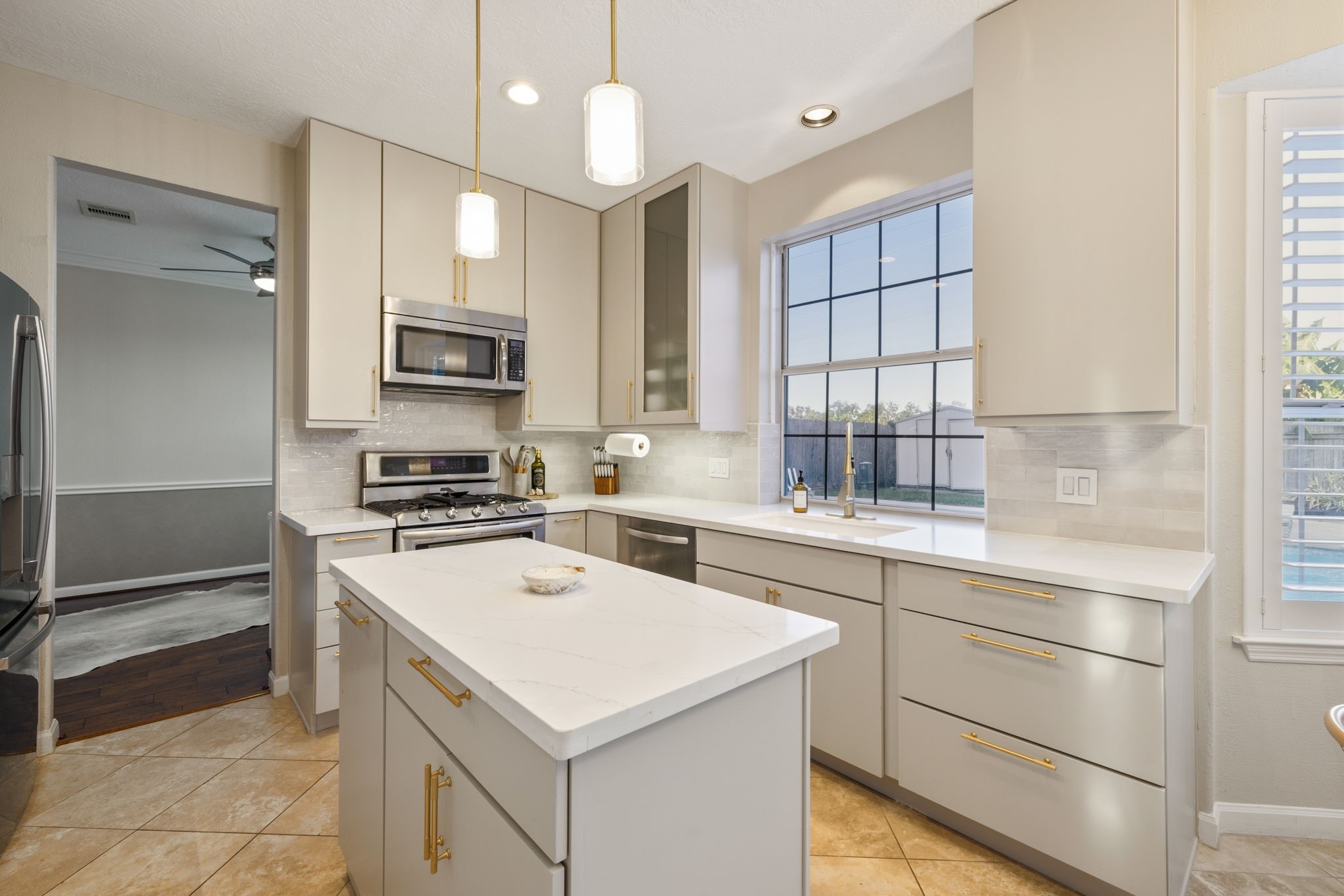 Stylish pendant lighting, abundant storage, and a sunlit window overlooking the pool complete this inviting kitchen.