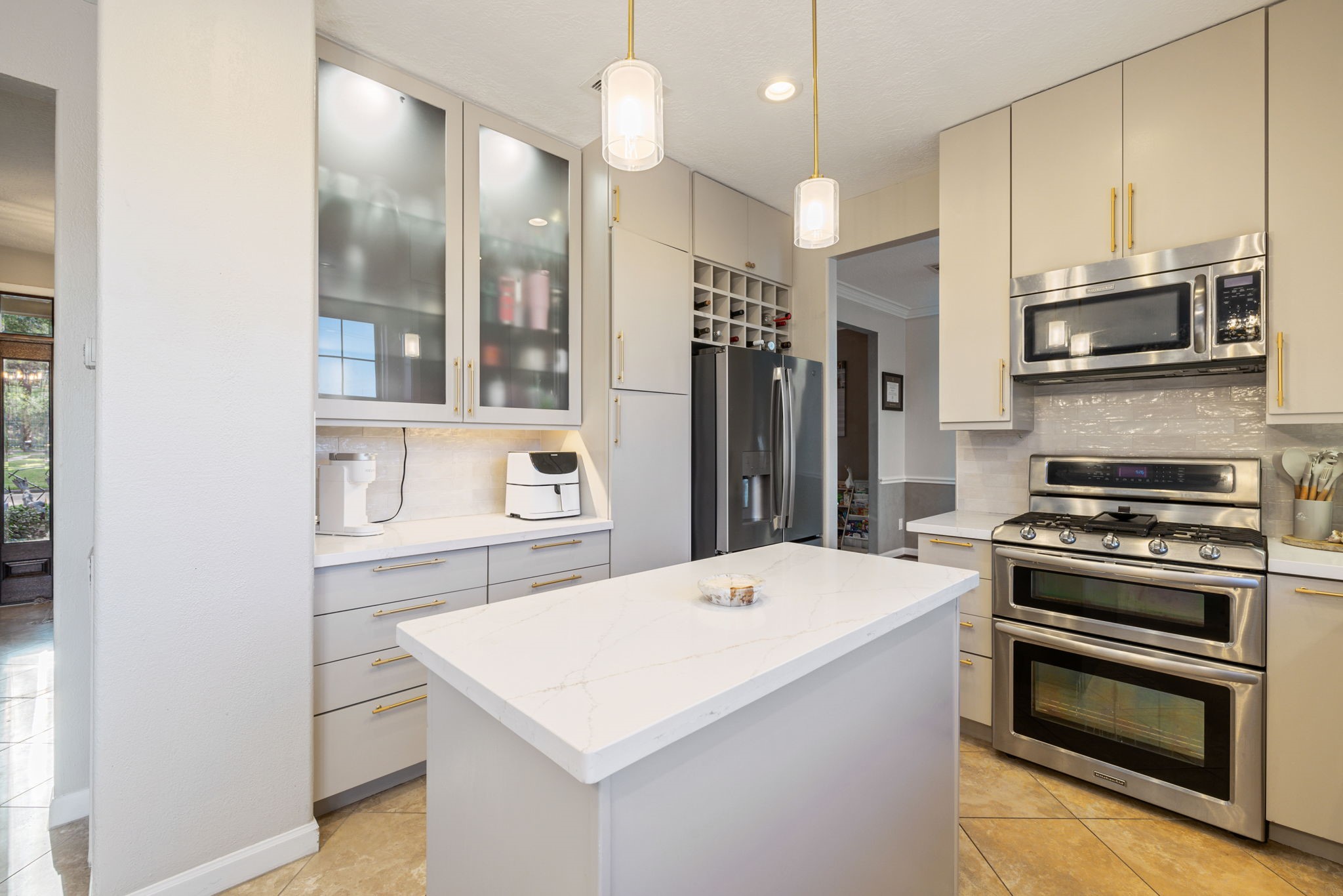 Another view of this beautifully updated kitchen featuring quartz countertops, elegant gold accents, a central island, and custom KraftMade cabinetry with soft-close cabinets and drawers.