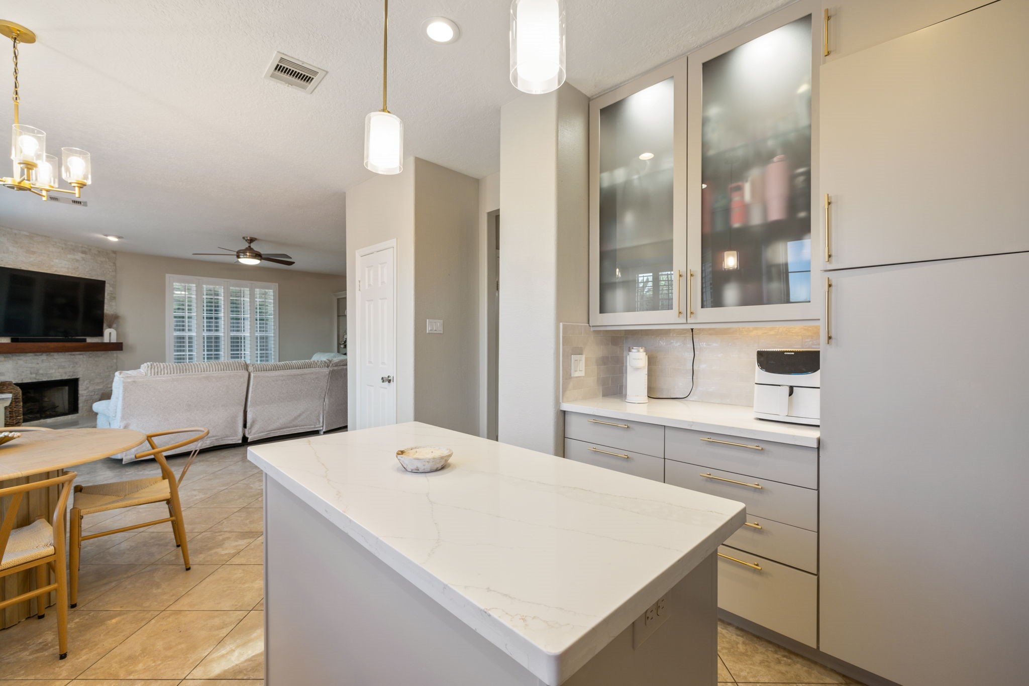 Frosted-glass cabinetry, designer lighting, and an open layout elevate this beautifully appointed kitchen.
