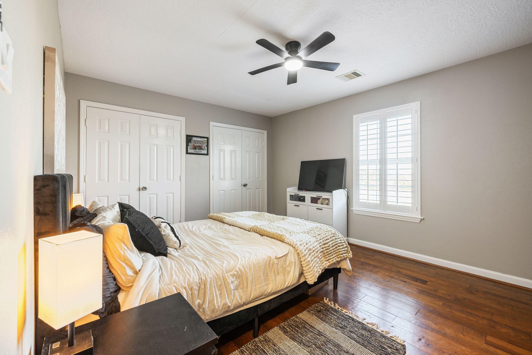 Another spacious bedroom with rich hardwood floors and a neutral paint color.  There are also double closets and abundant natural light, creating a cozy and inviting atmosphere.