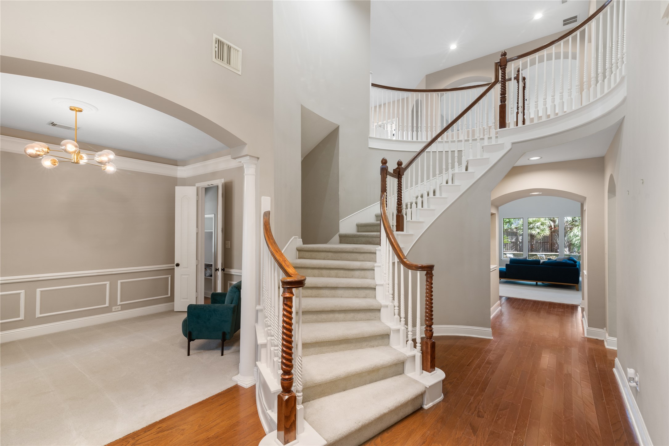 Elegant 2-story entry featuring a sweeping curved staircase, crisp white balusters, and warm wood accents.