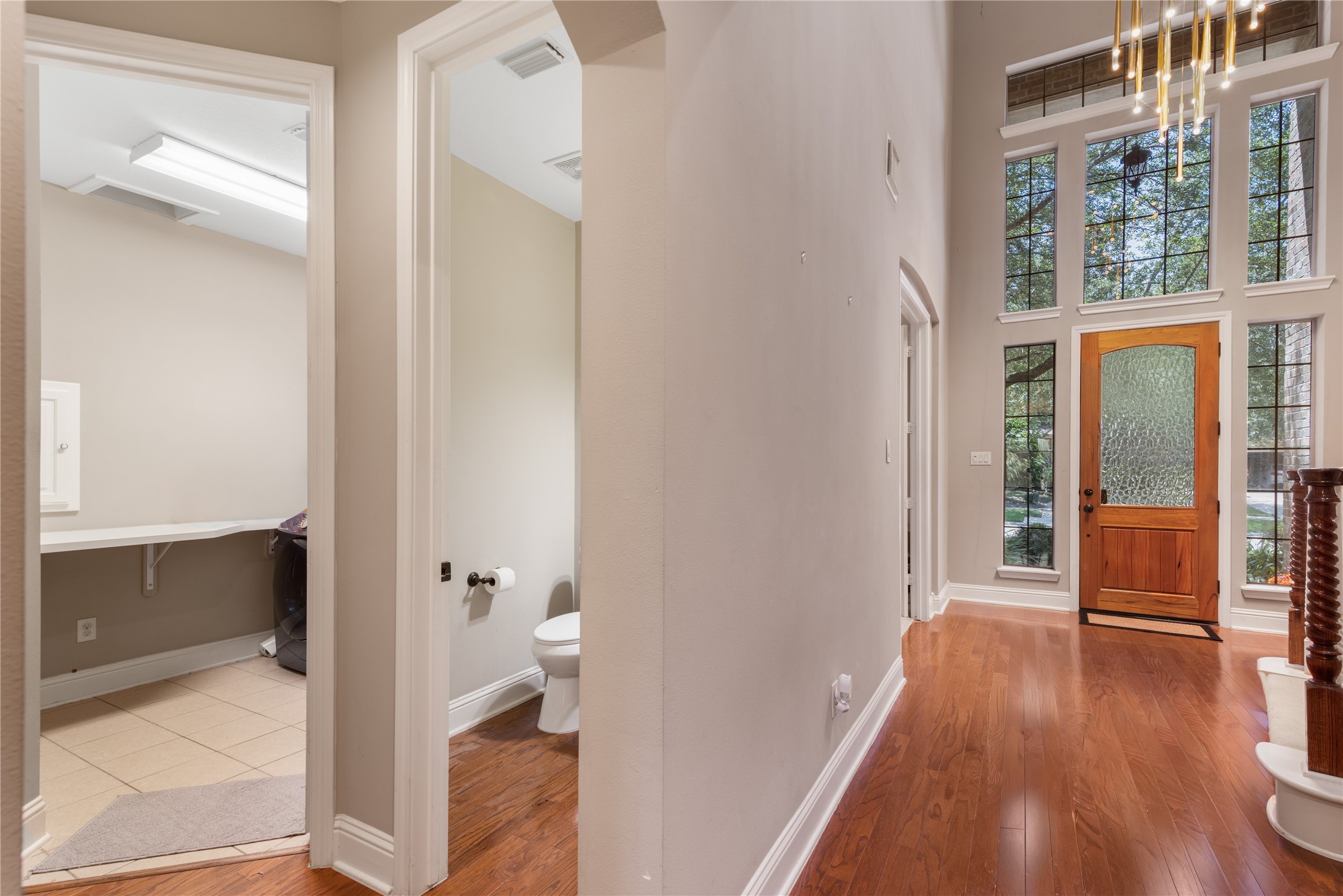 Beautiful entryway leads to the half bath and utility room, showcasing the home's functional layout and easy flow.  The modern lighting and neutral tones create a bright, welcoming first impression.