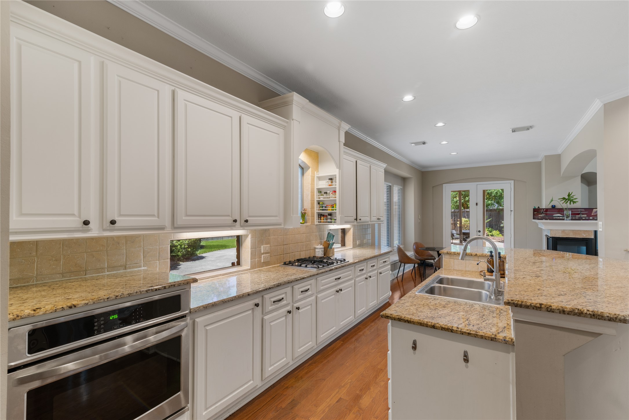 Spacious kitchen featuring white cabinetry, granite countertops, stainless steel appliances, and warm toned flooring.