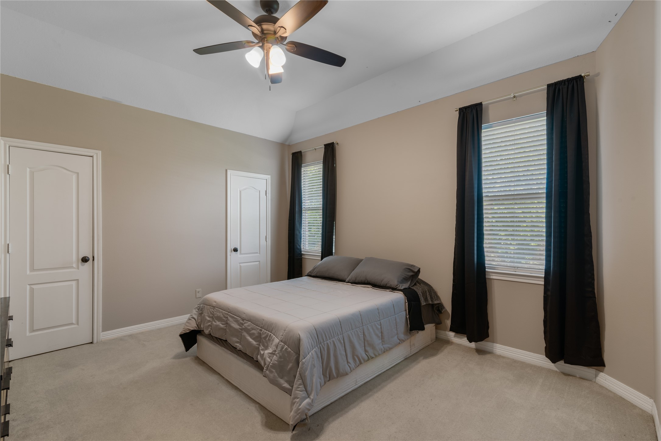 Another secondary bedroom upstairs featuring neutral tones, soft carpeting and large windows for natural light.