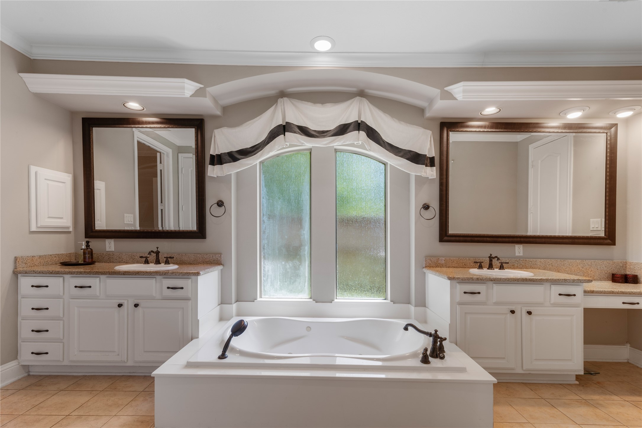 Elegant master bath featuring dual vanities with granite countertops and a large soaking tub for a spa-like retreat within the suite.