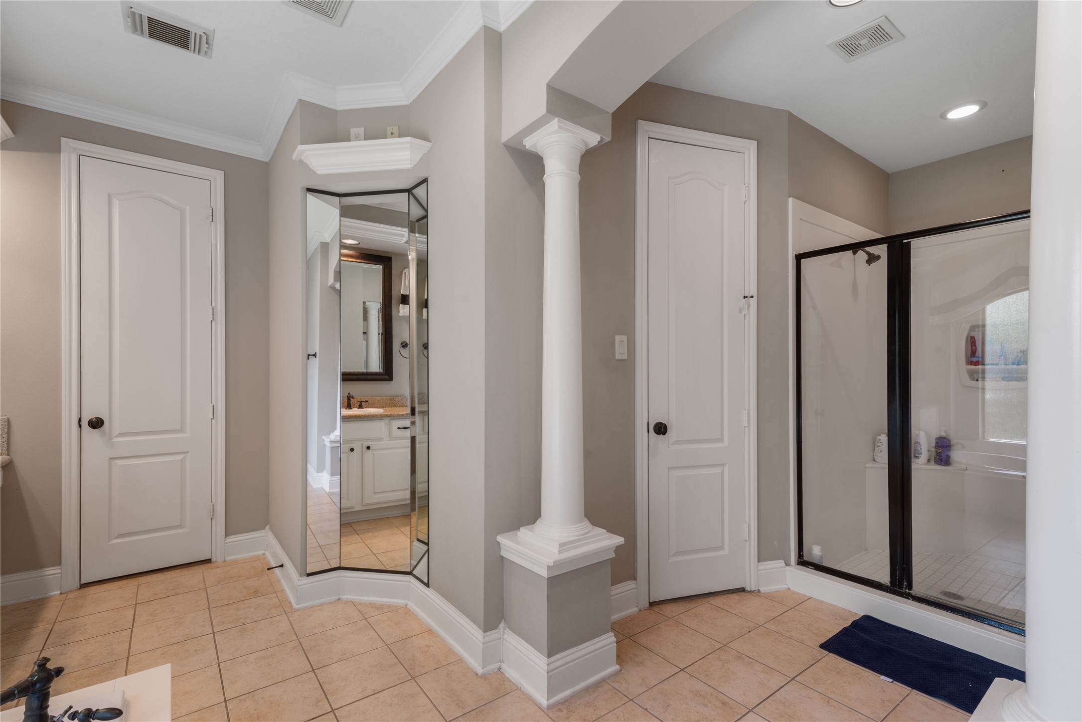 Beautifully designed bathroom with separate glass-enclosed shower, tile flooring, recessed lighting, and elegant architectural details.