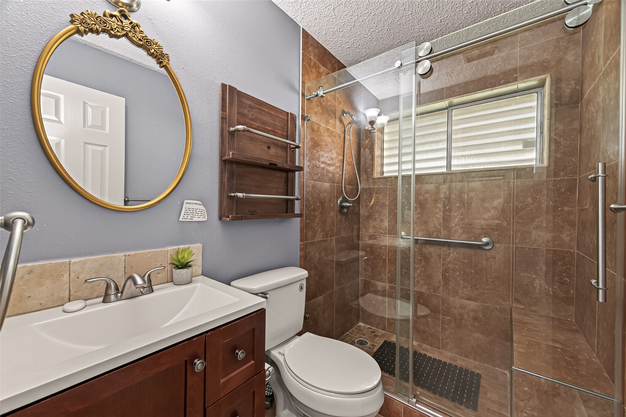 Updated bathroom with a large walk-in tiled shower, frameless glass enclosure, built-in bench, modern vanity, and abundant natural light. Thoughtfully designed for both style and functionality.