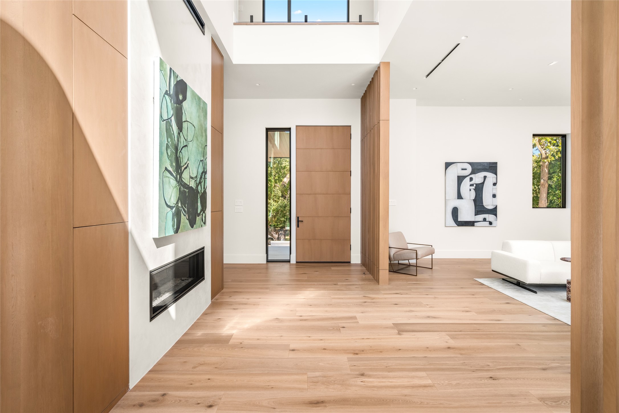 The home's entry is defined by soaring ceilings, abundant natural light, and refined architectural details, with a custom wood entry door, white oak flooring, and thoughtfully integrated millwork creating a warm yet sophisticated welcome.