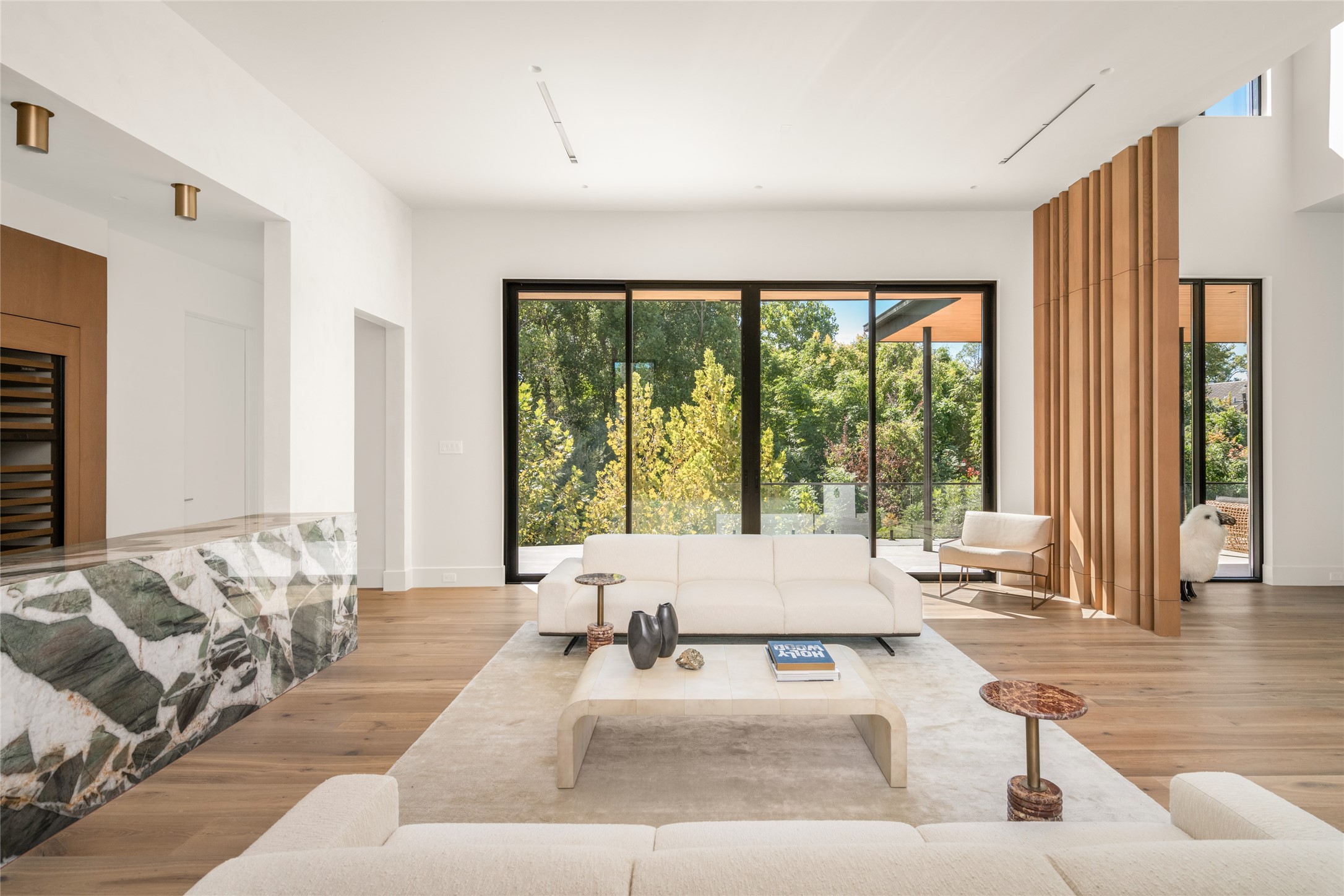 Back inside, the bar opens to an expansive gathering space with floor-to-ceiling glass, a private terrace, and beautiful treetop views, creating a seamless connection between indoor and outdoor living.