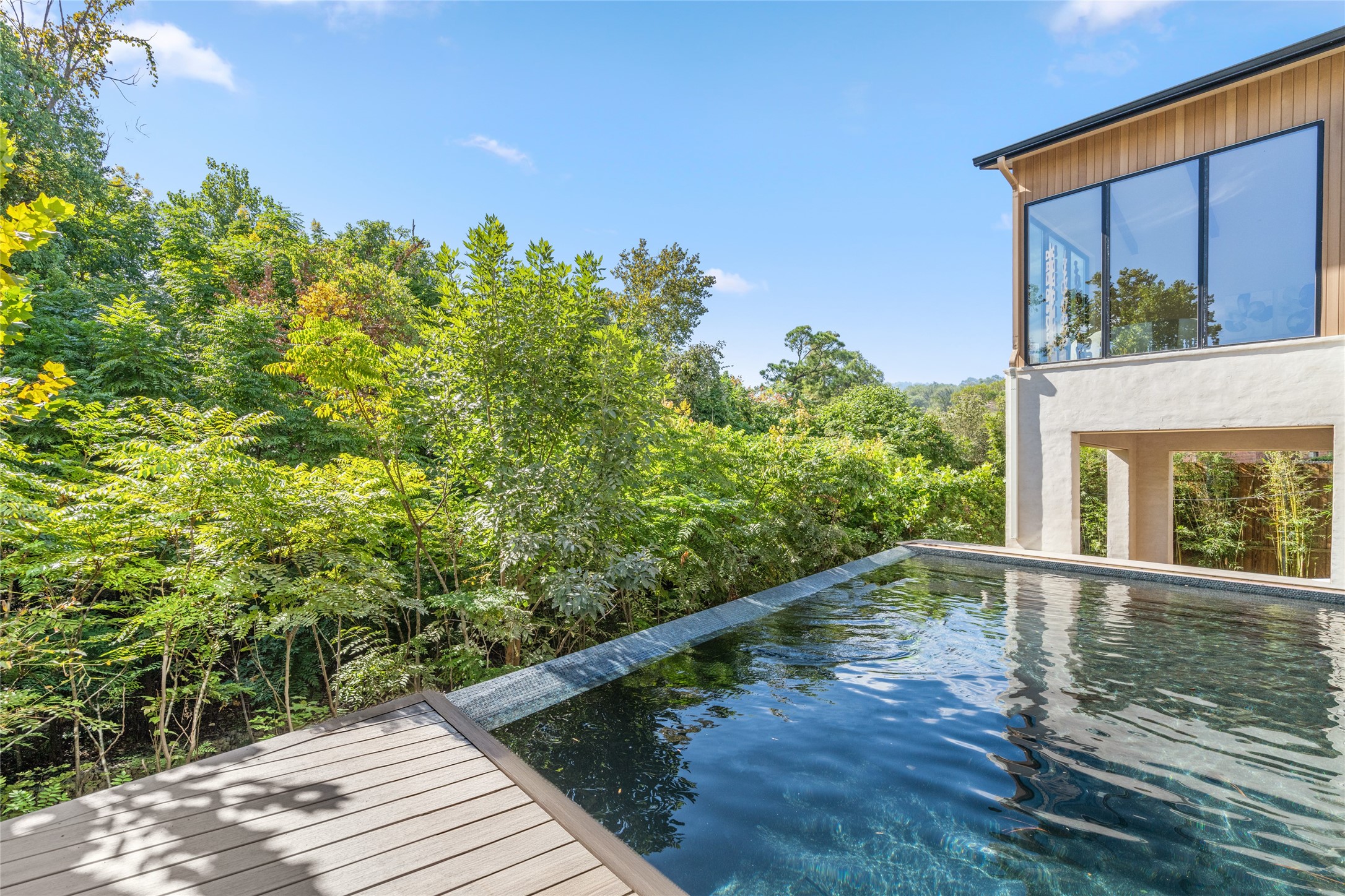Suspended above the wooded landscape, the vanishing-edge pool creates a stunning visual connection with the surrounding greenery, offering a peaceful setting that feels worlds away from the heart of River Oaks.