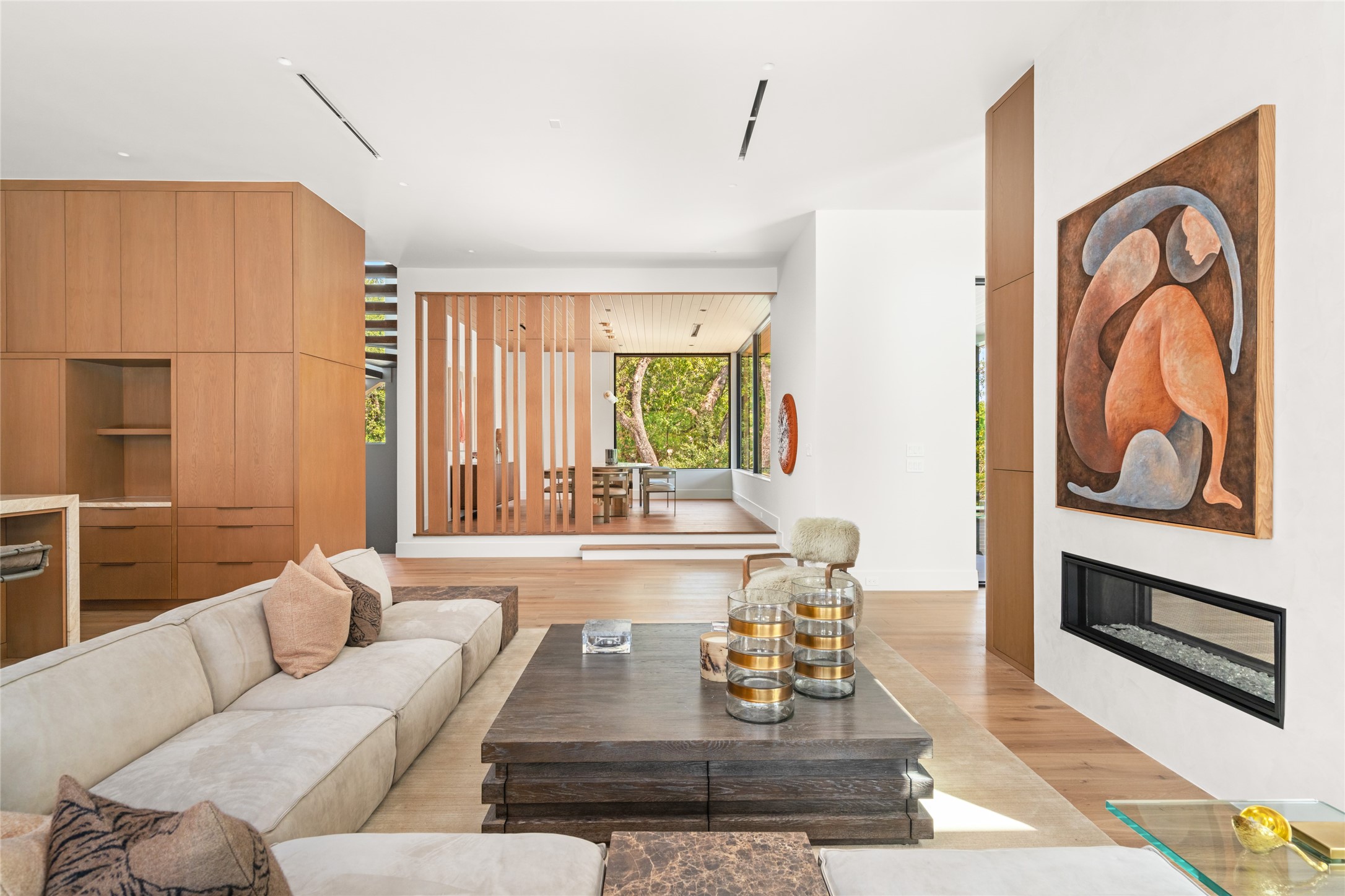 The family room transitions beautifully into the elevated dining room, where a double-sided fireplace, custom white oak detailing, and thoughtfully designed architectural elements create a warm and inviting setting for entertaining.
