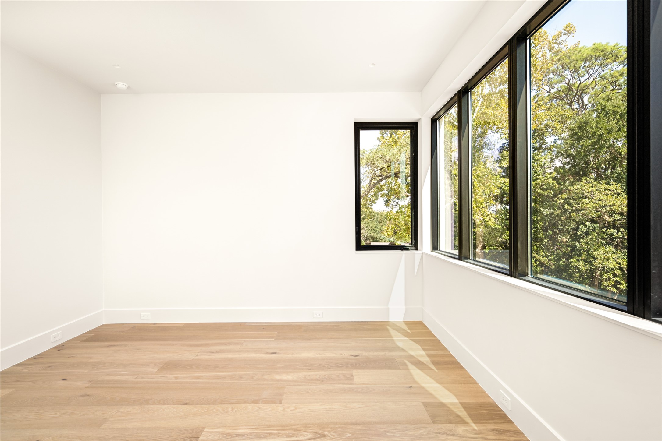 A striking wall of expansive windows defines this spacious, light-filled bedroom suite, bringing the outdoors in and creating a beautiful connection to the surrounding landscape.