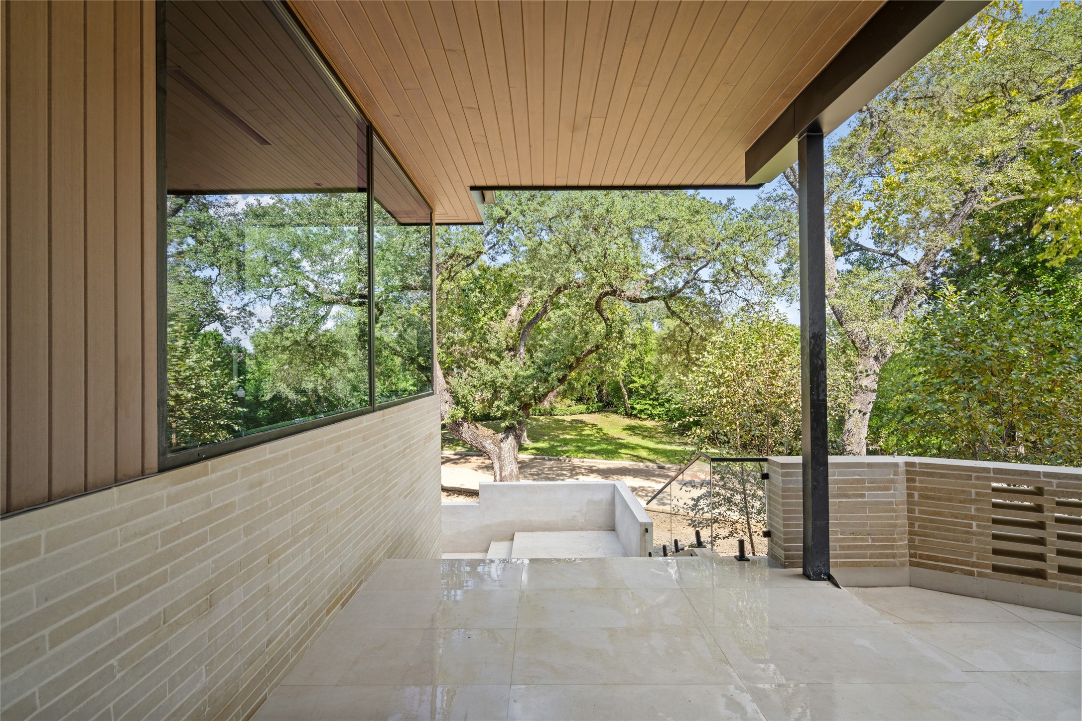A welcoming covered entry features warm wood ceilings, natural stone flooring, and clean architectural lines, offering a beautiful transition from the outdoors into the home.