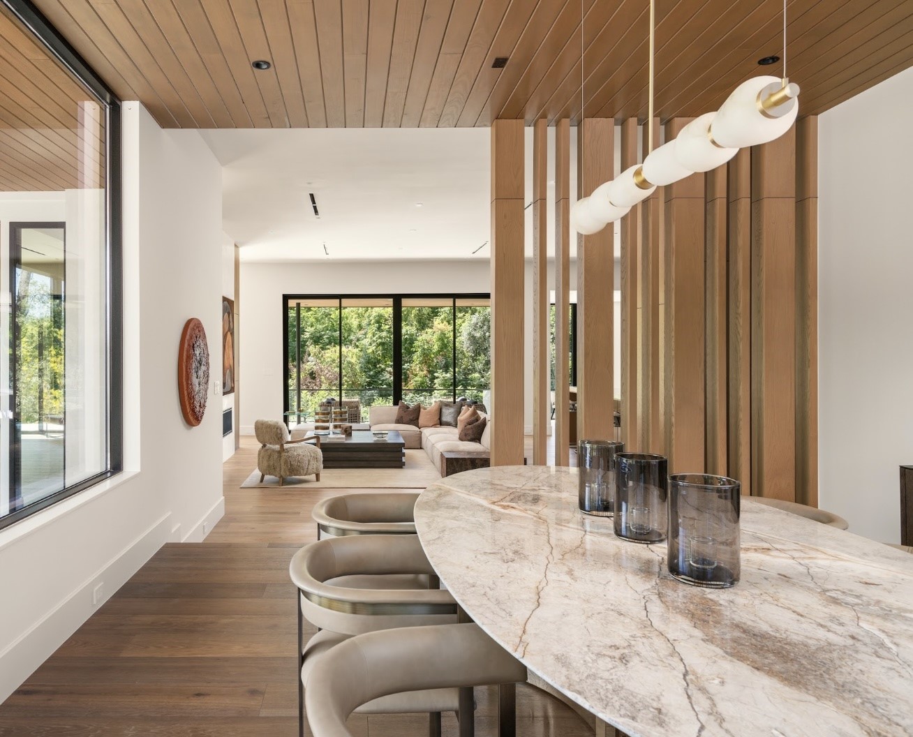 From the dining room, the home's thoughtful design comes into focus, with warm wood ceilings, beautiful architectural glass, and views extending toward the adjoining family room and entertaining bar.