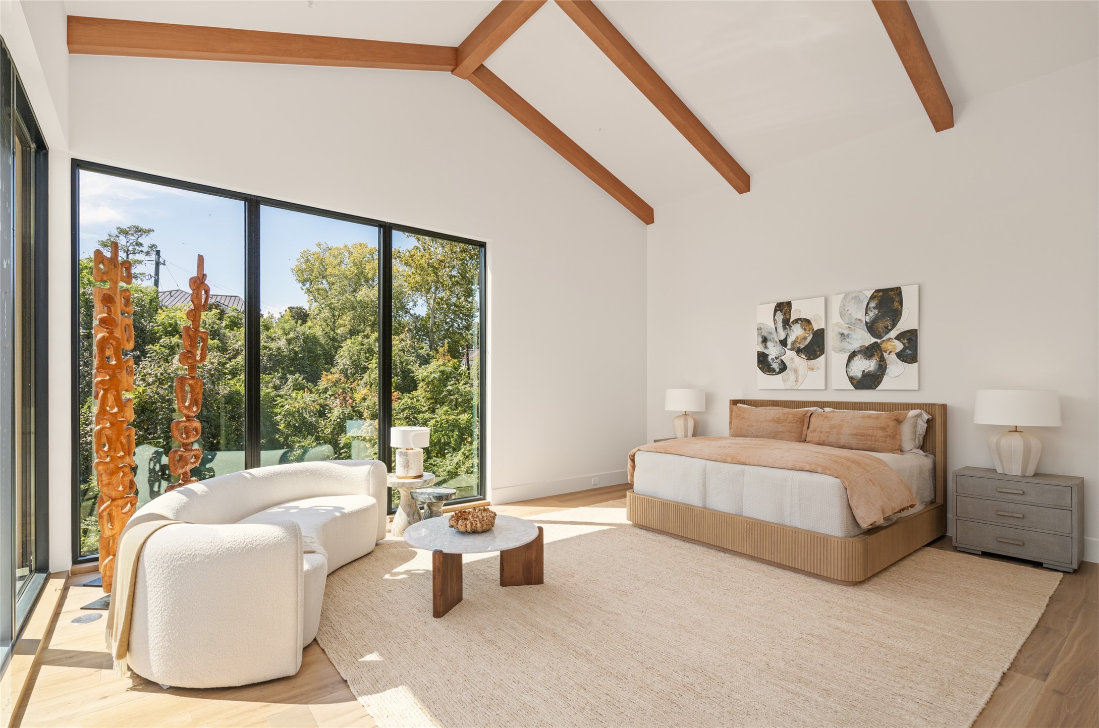 The primary suite is a peaceful retreat, featuring a dramatic 20-foot vaulted ceiling with exposed wood beams and walls of glass that bring in natural light and frame the surrounding treetops.