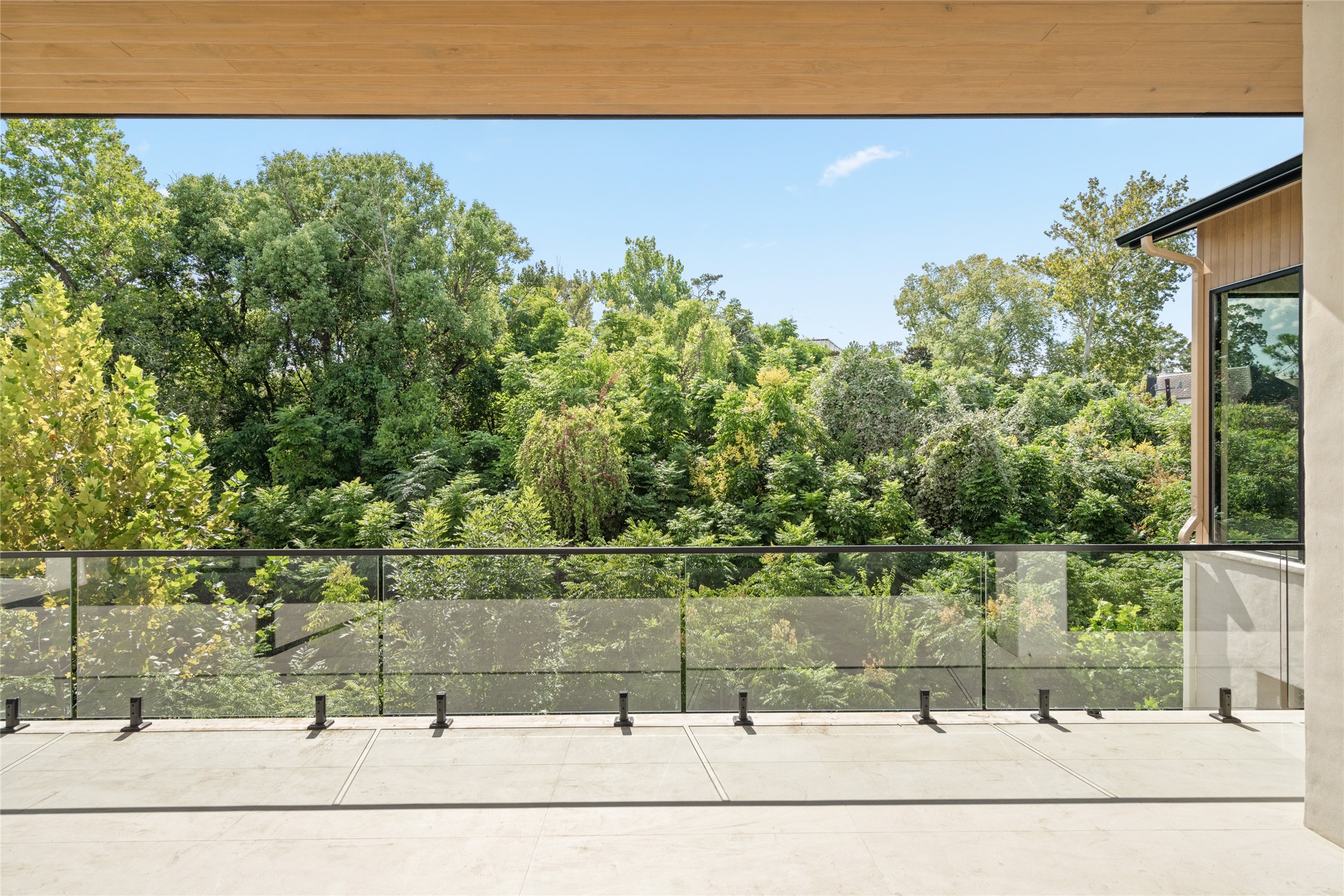 A beautiful canopy of trees creates a peaceful backdrop for the expansive main-level terrace, offering a sense of privacy and a wonderful place to enjoy the outdoors.