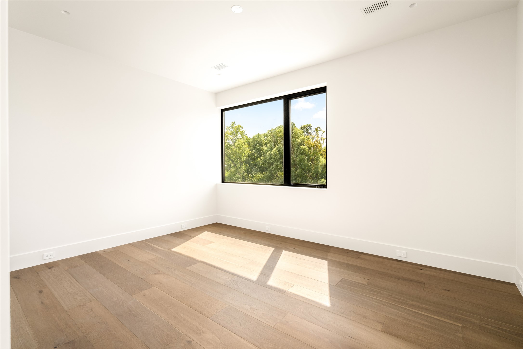 Sunlight pours into this spacious bedroom suite through a large picture window, creating an airy atmosphere with plenty of flexibility for furniture placement.