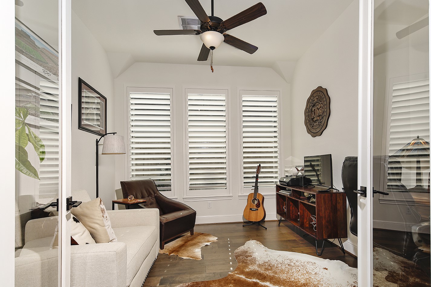 This spacious study features a stunning wall of plantation shutters and elegant double glass doors, providing both beautiful natural light and complete privacy.