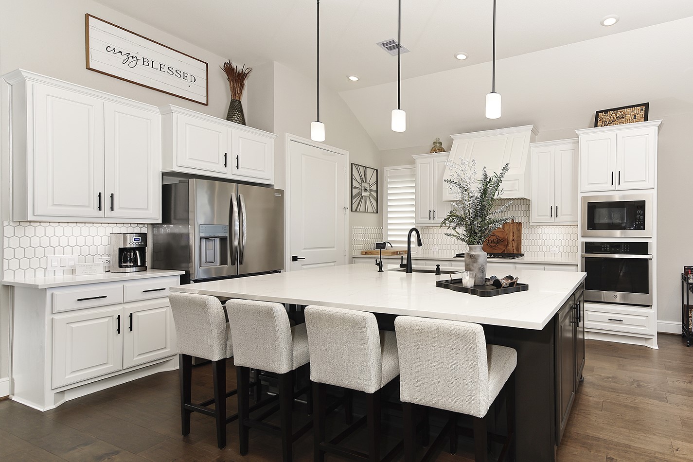 This impressive kitchen features an oversized island with ample seating, crisp white quartz countertops, and sleek stainless steel appliances.