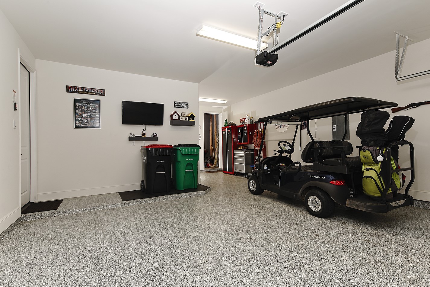 Oversized two-car garage with additional space for a golf cart and dedicated storage.