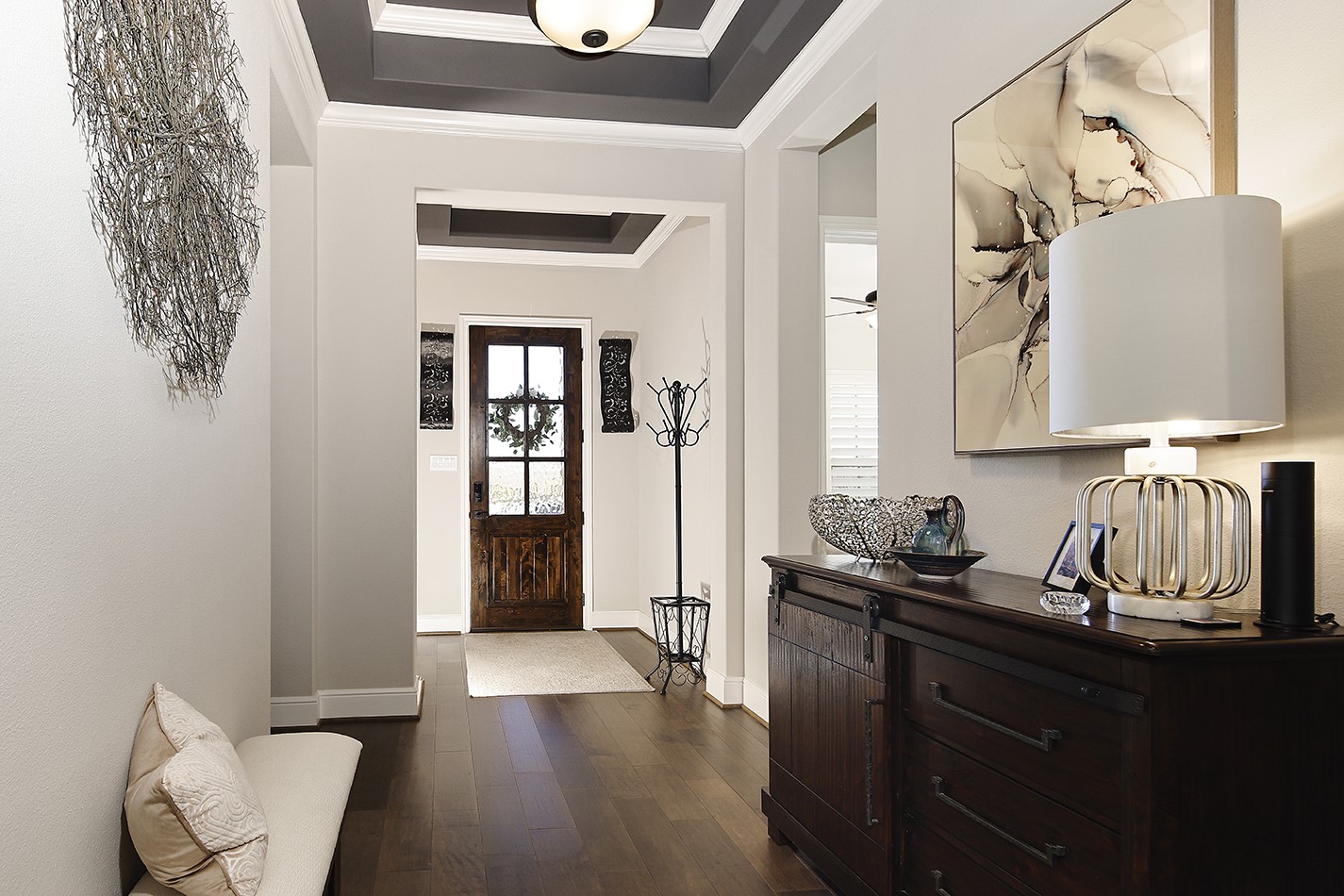 This home features exquisite custom appointments throughout, highlighted by a rich, accent-colored tray ceiling that perfectly contrasts with the designer white walls and beautifully complements the warm wood flooring.
