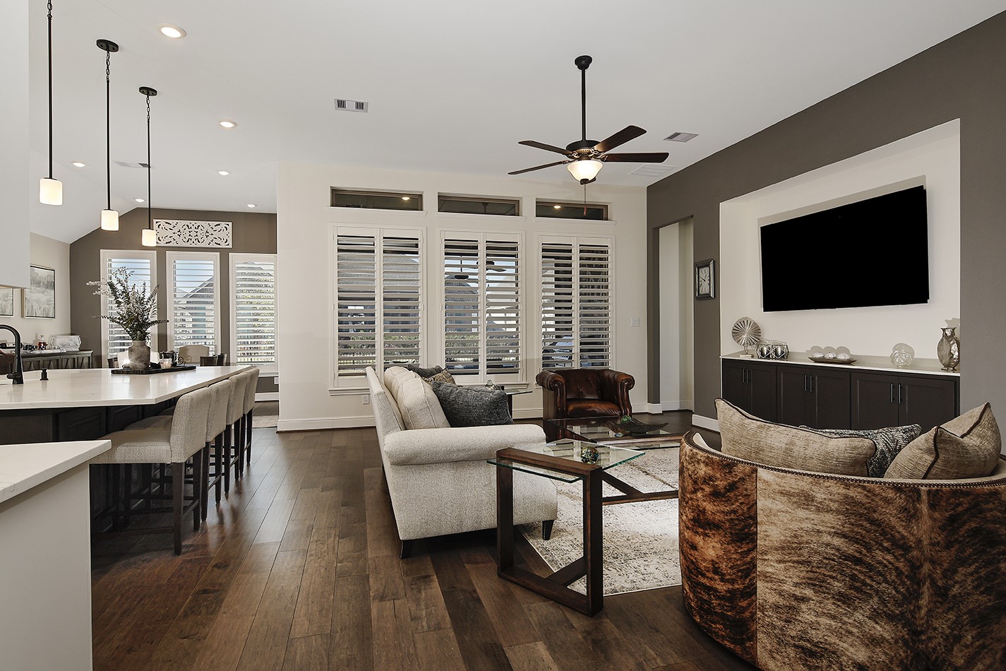 This home features an open-concept floor plan designed for seamless entertaining and family interaction. The striking wall of windows, accented by plantation shutters and transoms, offers a beautiful view of the covered lanai.